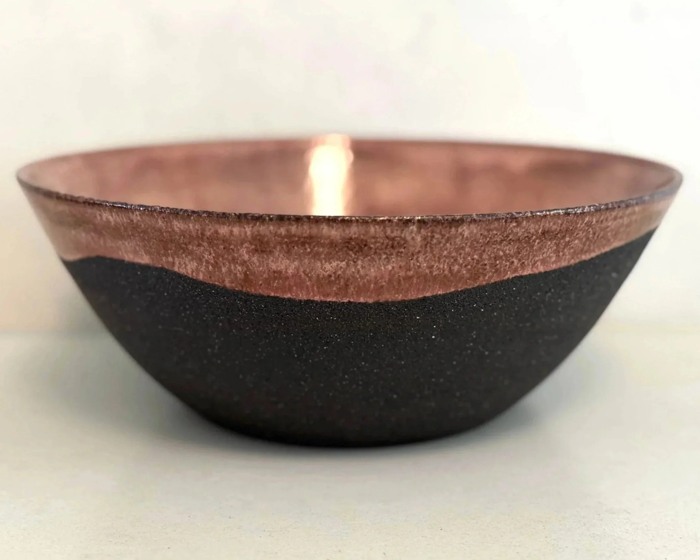 Close-up of a copper and black bowl placed on a white surface.