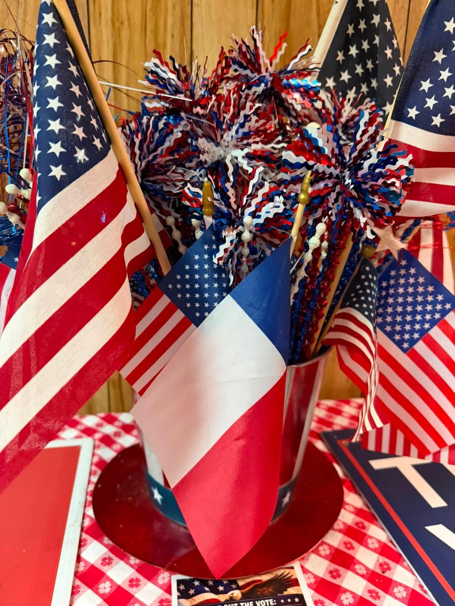 Red, white, and blue patriotic decorations with American flags and star-themed items on a red and white checkered tablecloth.