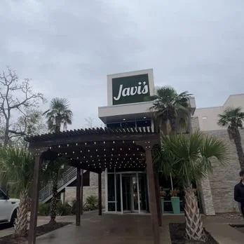 Javi's restaurant entrance with a wooden canopy and palm trees.