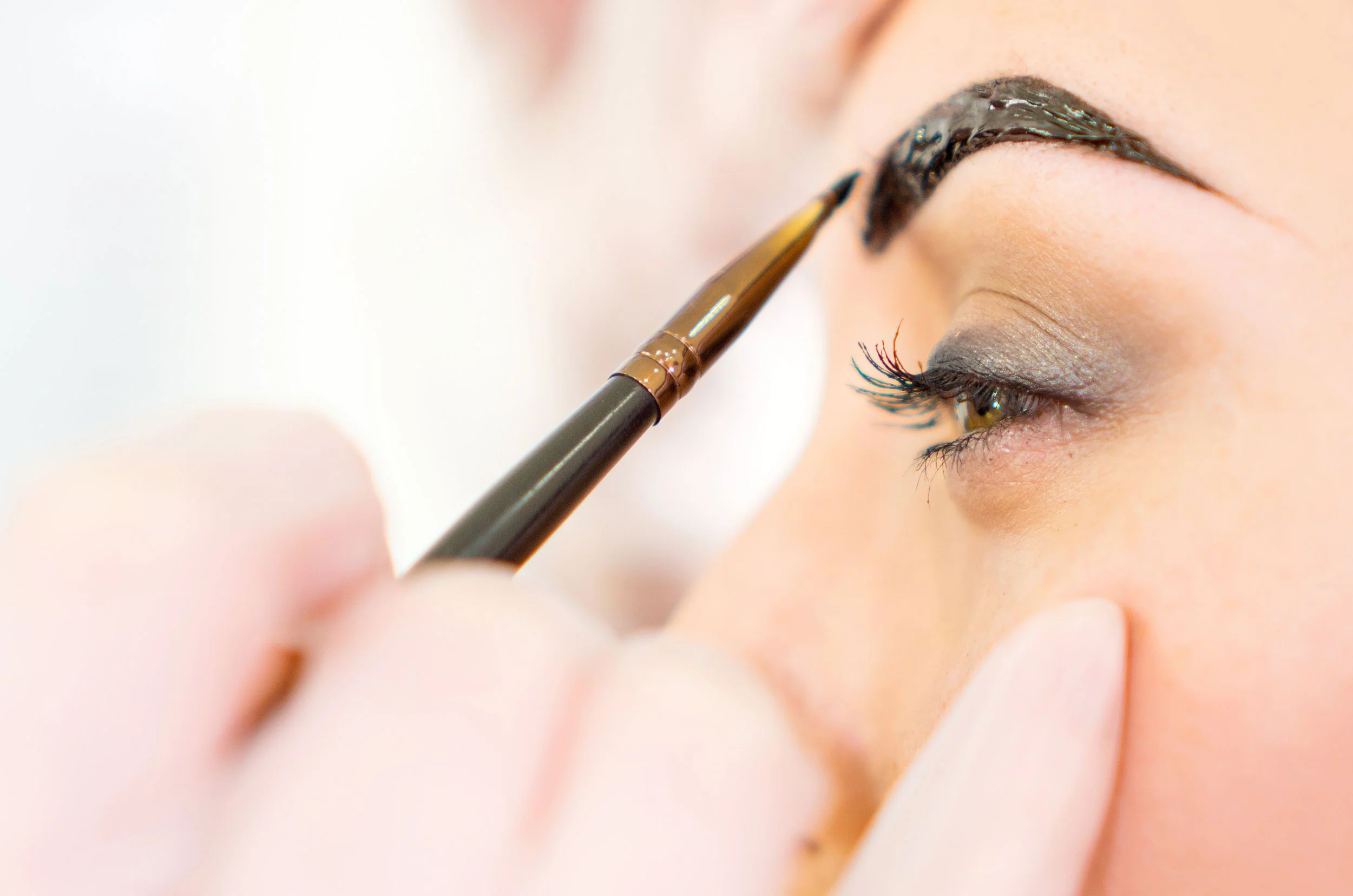 A close-up of a person applying black lipstick with a brush.