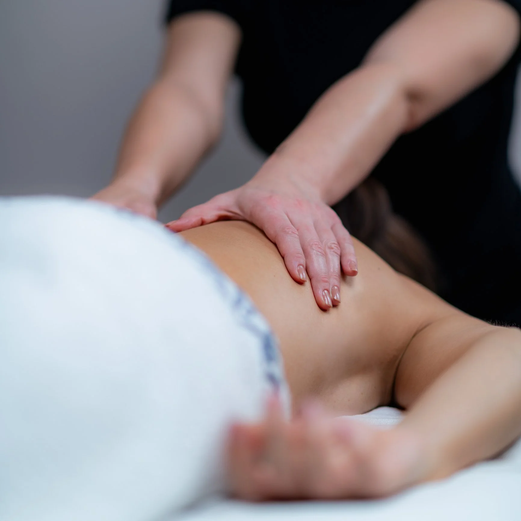 Close-up of a person receiving a massage, with hands pressing on their back.