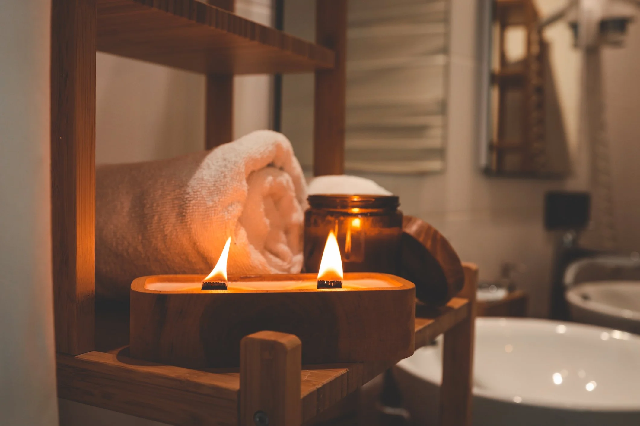 Candles and towels on a wooden shelf in a bathroom or spa setting.