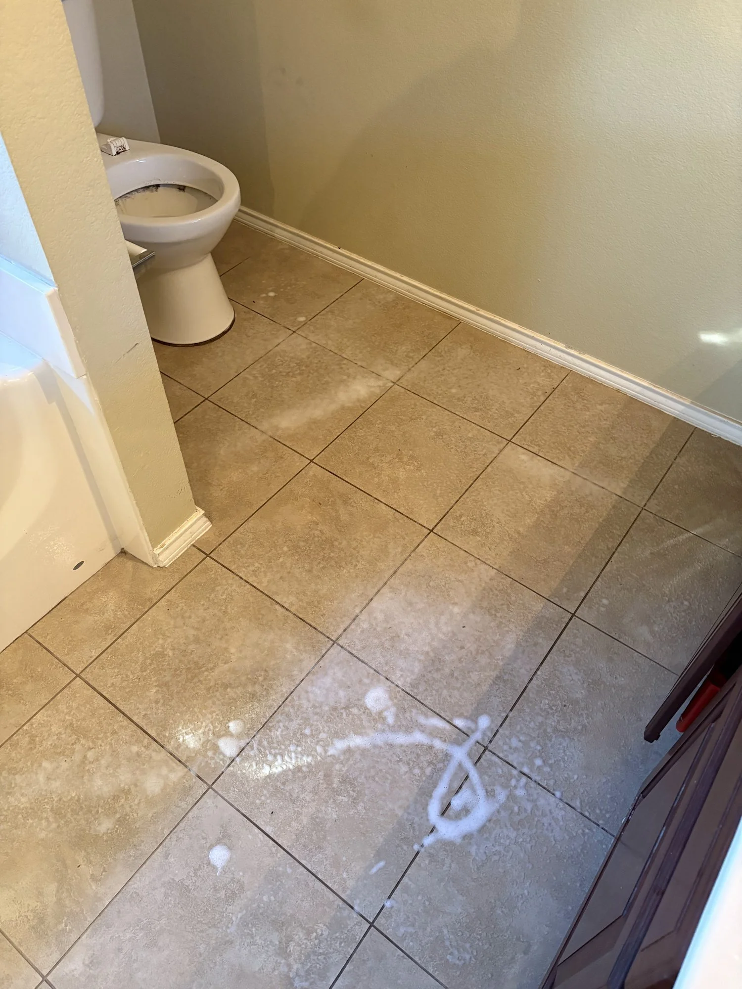Technician disinfecting a bathroom tile floor with EPA-registered disinfectant during biohazard and blood cleanup in Dallas–Fort Worth