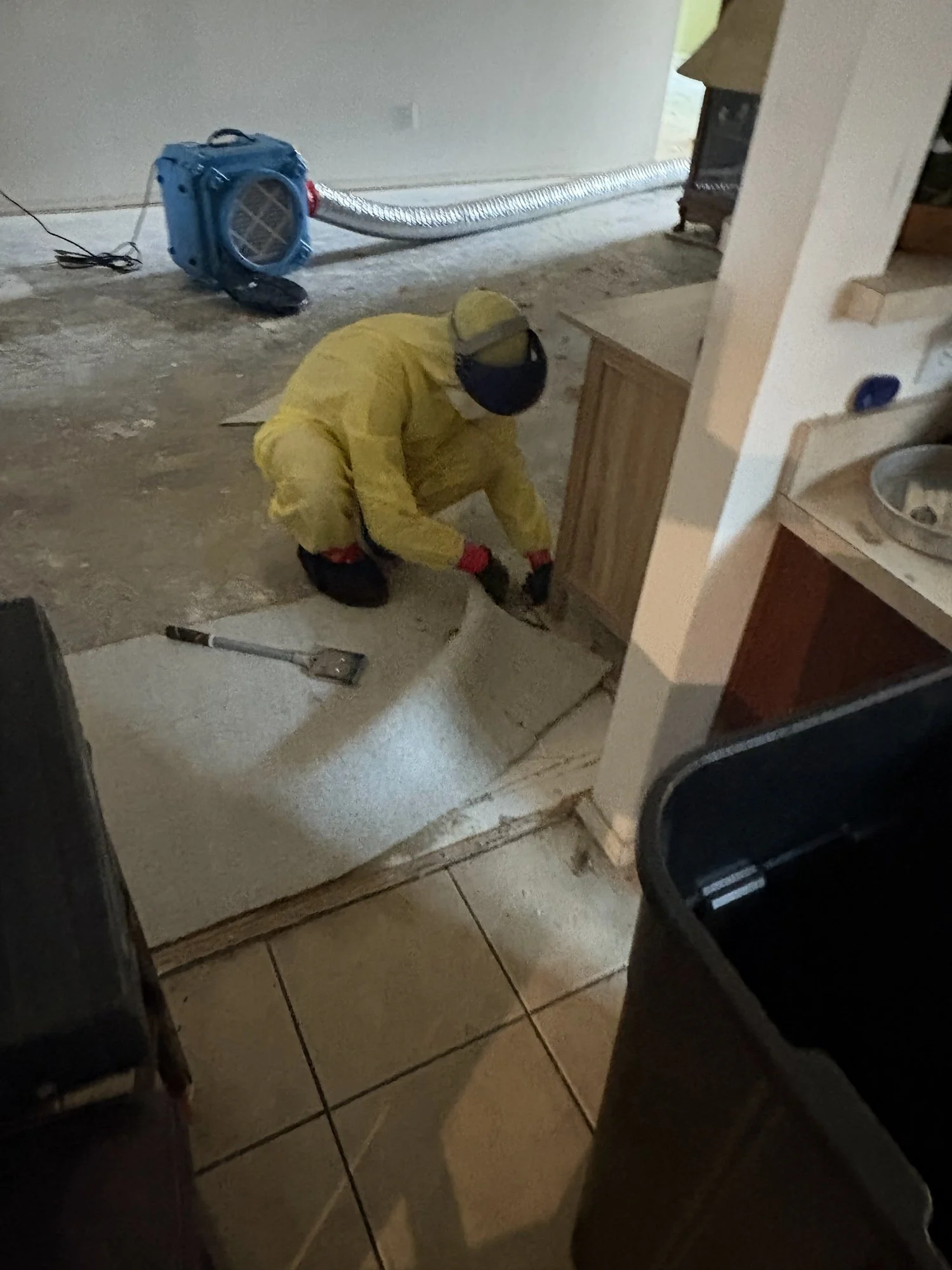 IICRC-certified technician in protective gear removing contaminated flooring during biohazard cleanup in Dallas–Fort Worth