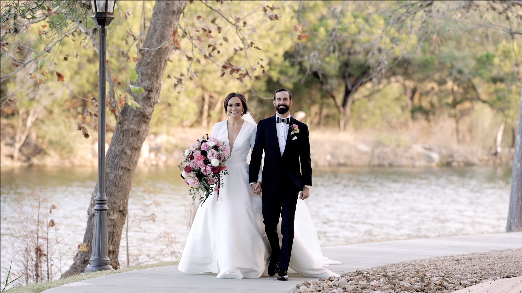 Bride and groom walking hand in hand at sunset.