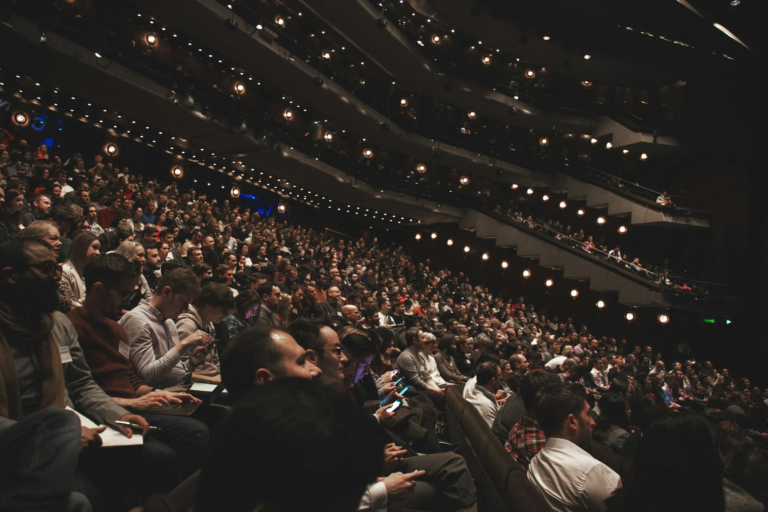 Large audience seated in a multi-level theater auditorium