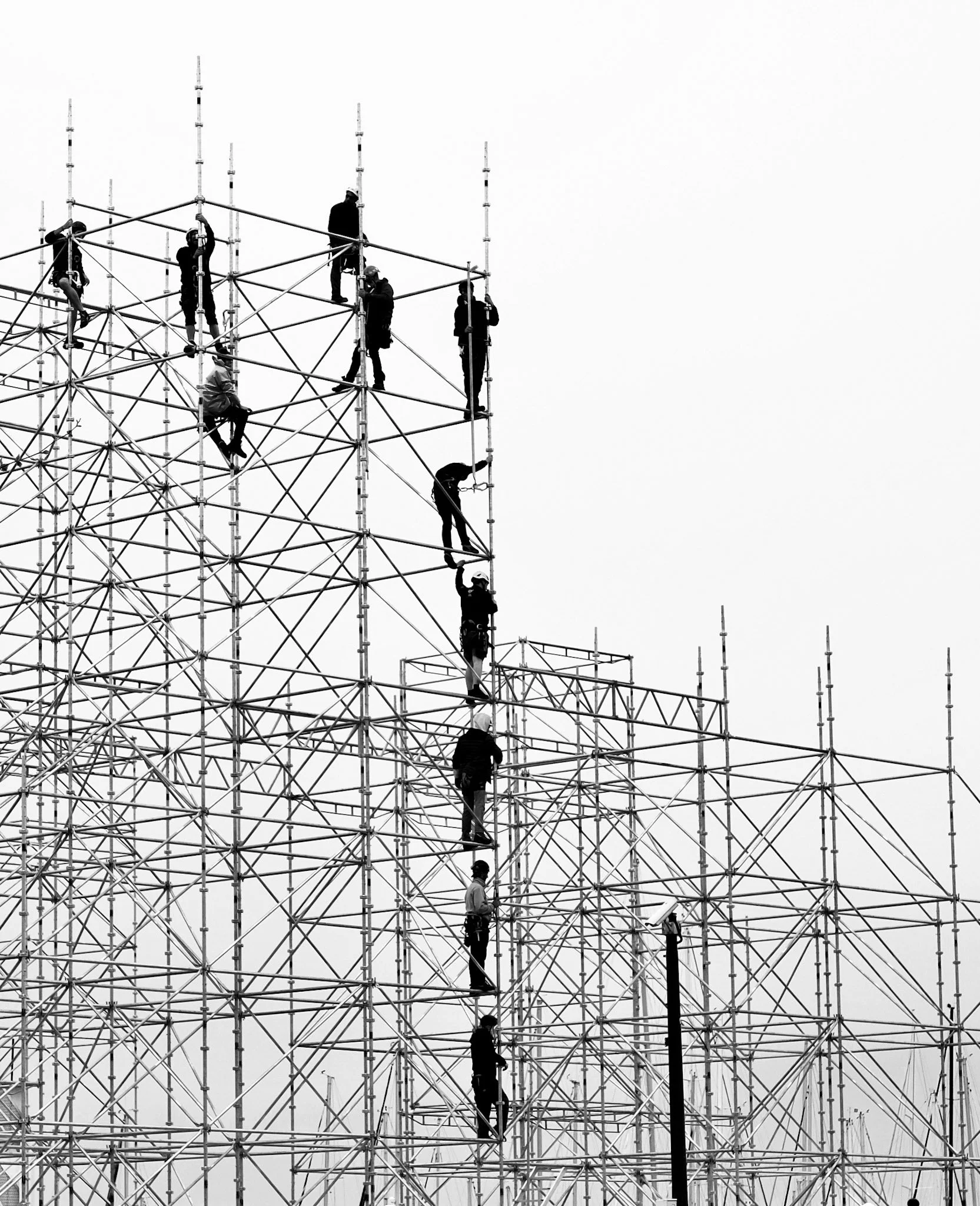 Workers in safety gear constructing a large metal scaffolding structure.