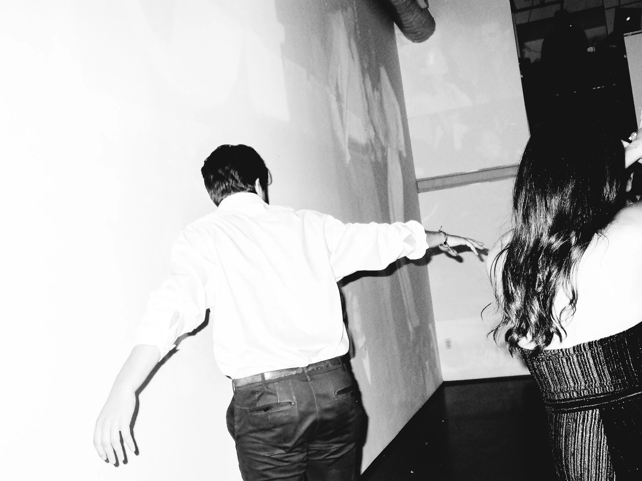 Man and woman holding hands, dancing indoors, black and white photo.