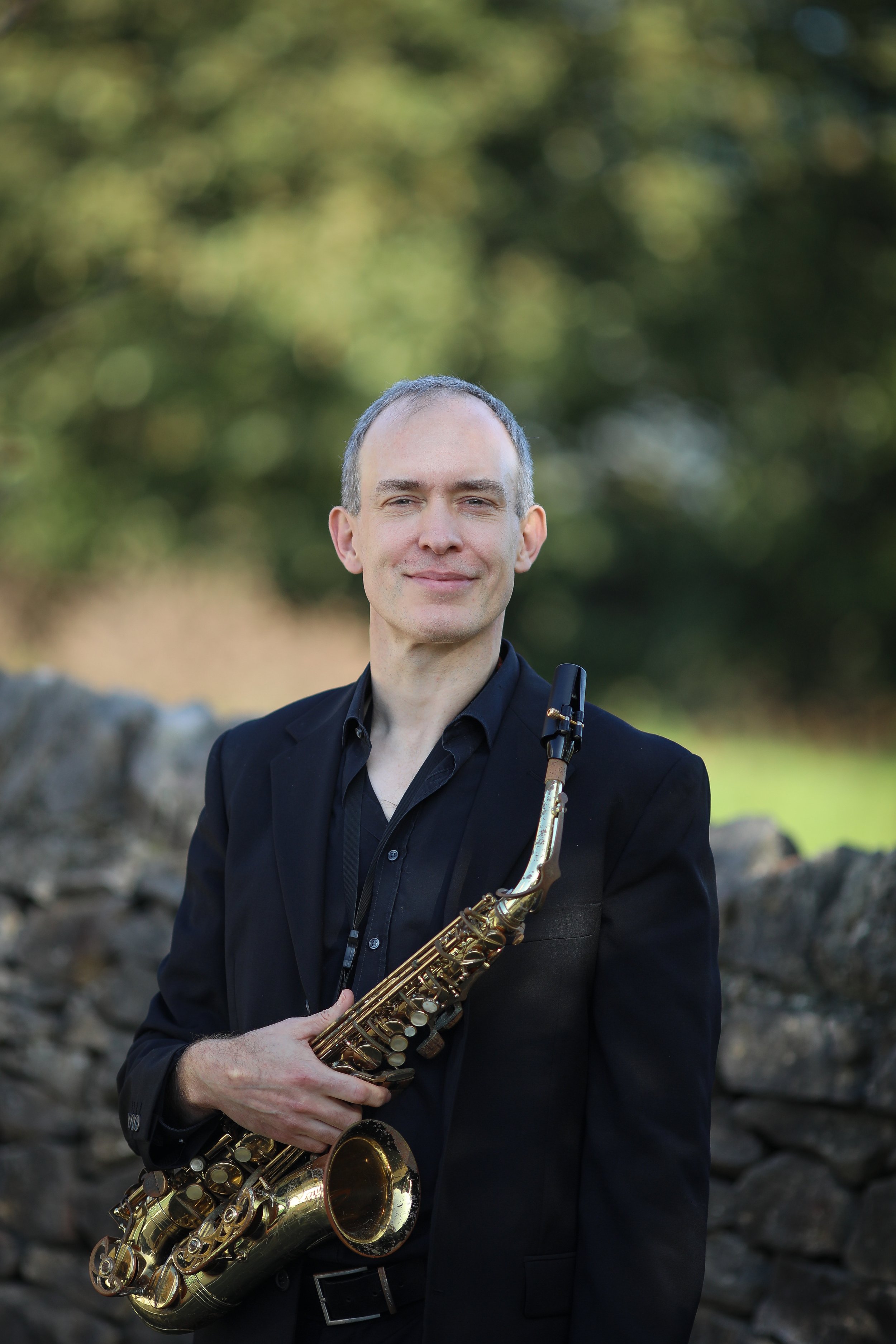 Toby, saxophone player with Arundo5, holding his saxophone outdoors.