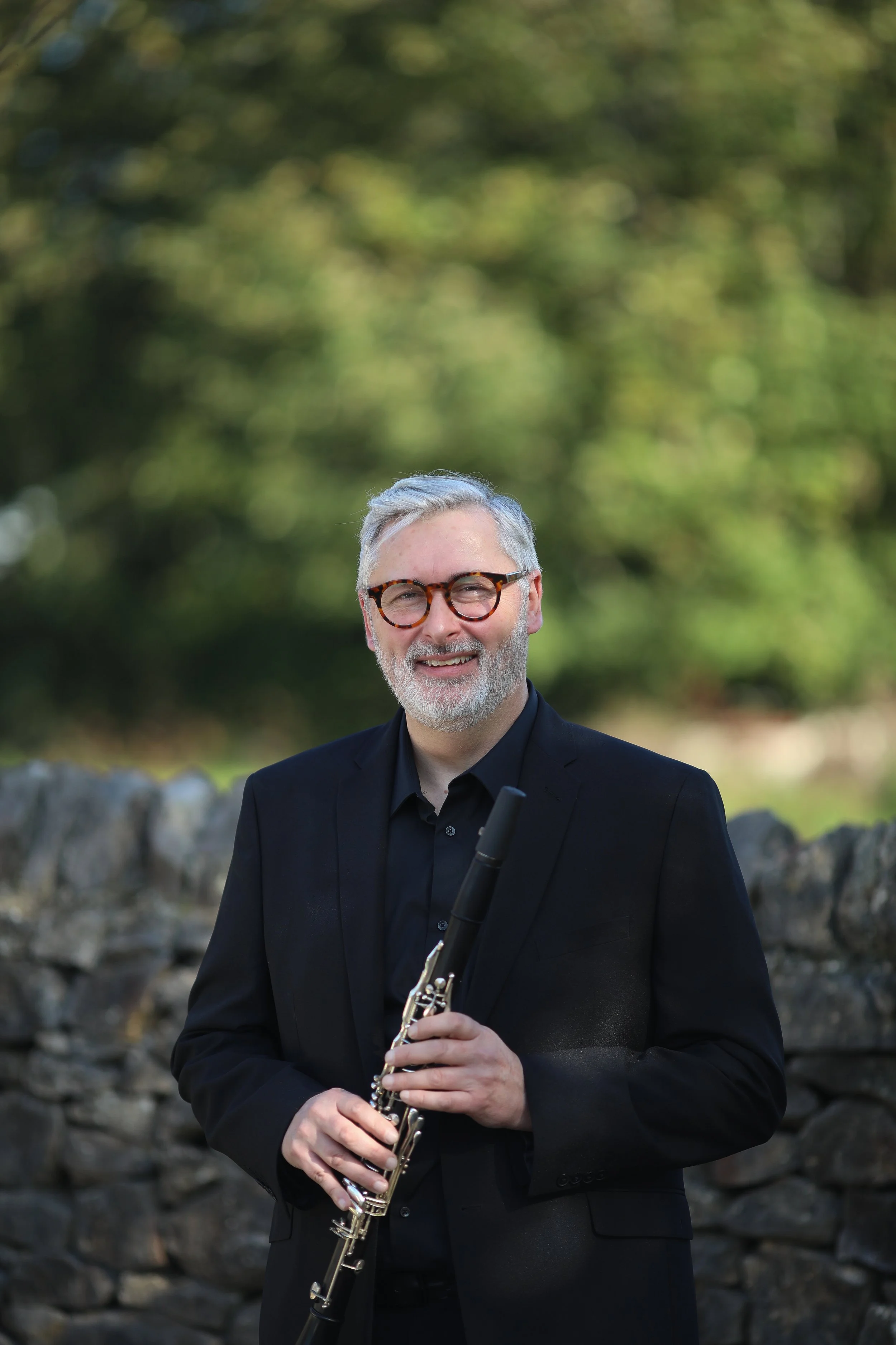 Stuart, clarinet player with Arundo5, holding his clarinet outdoors.
