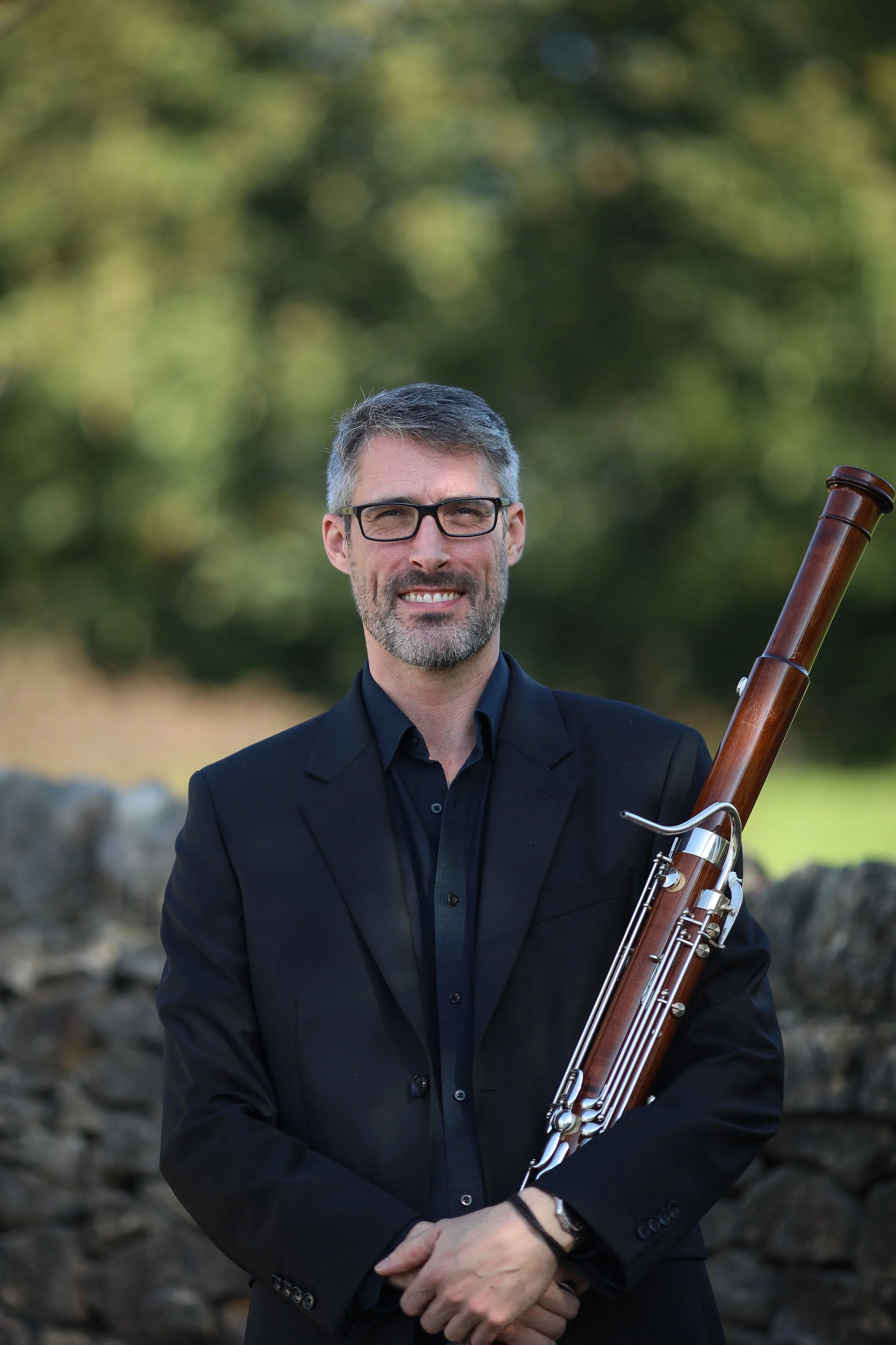 Howard, bassoon player with Arundo5, holding his bassoon outdoors.