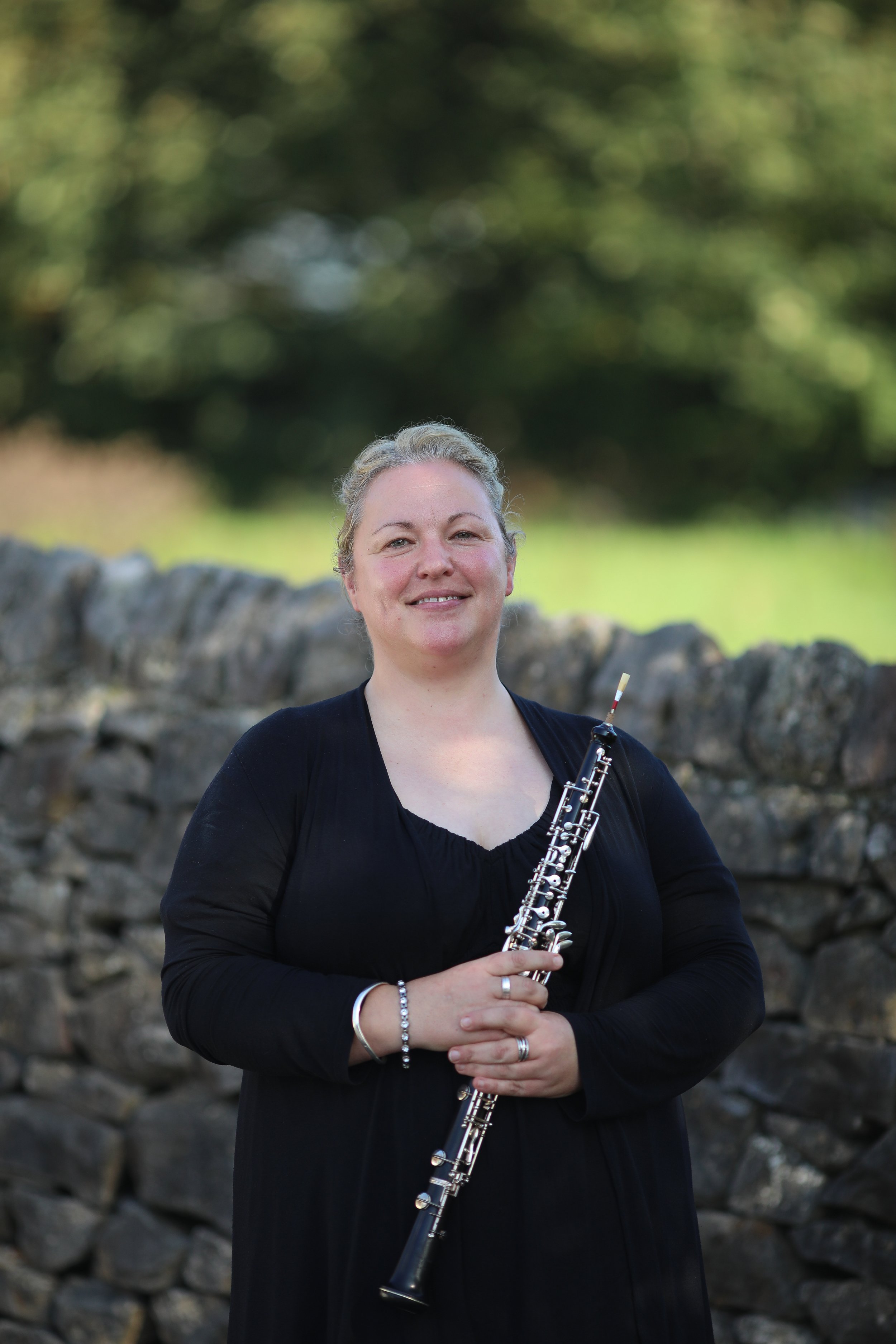Manon, oboe player with Arundo5, holding her oboe outdoors.