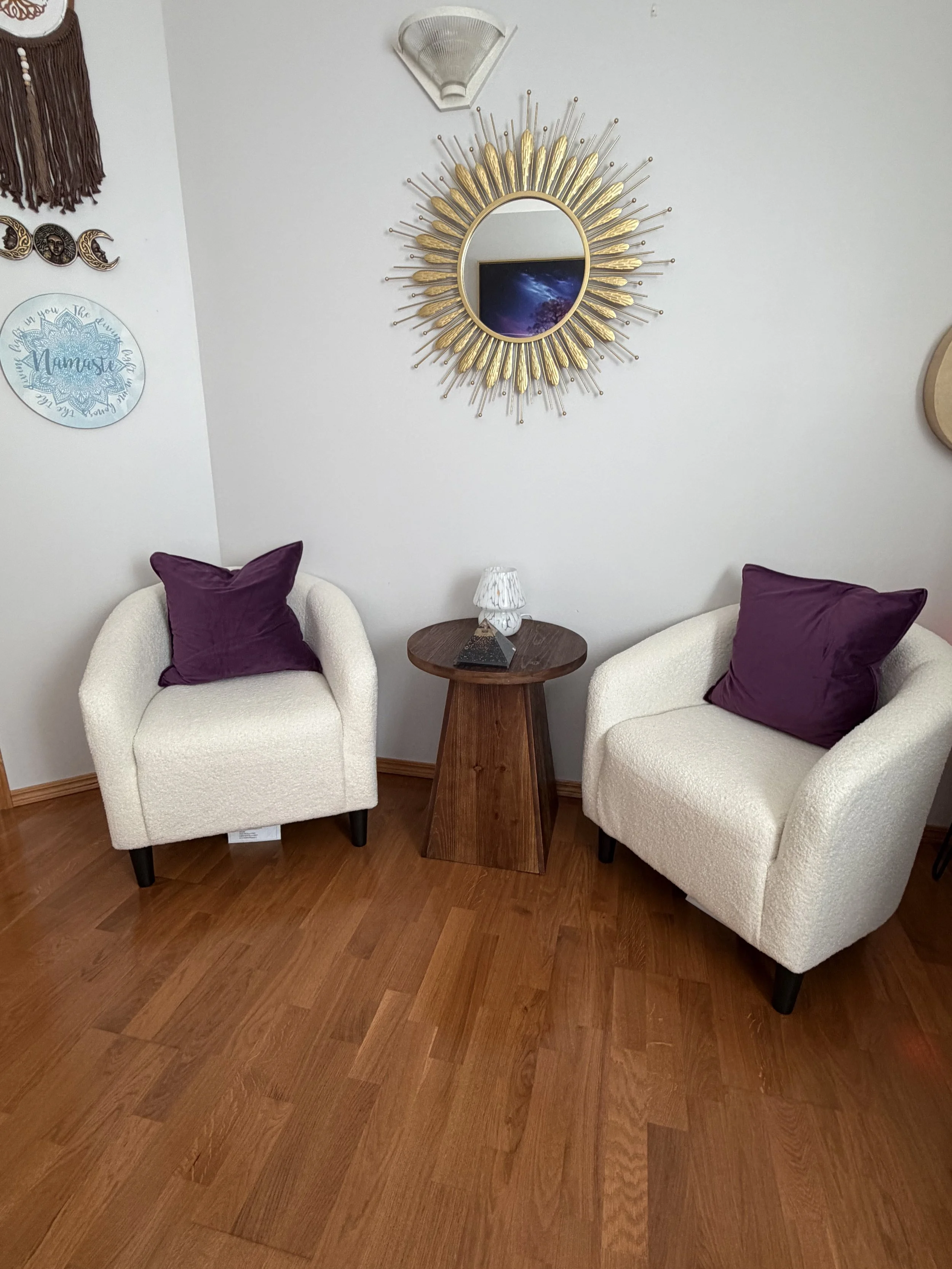 Cozy seating area with two cream chairs and purple cushions at Stardust & Sol in Stonewall.