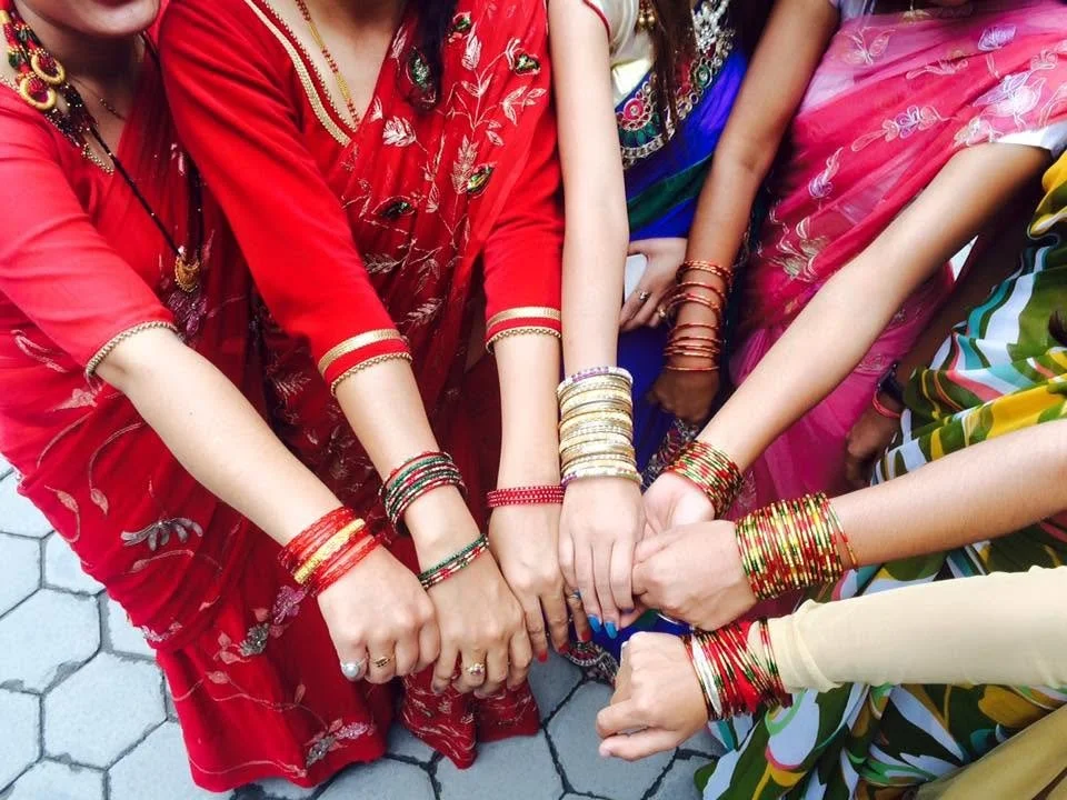Group of women in colorful traditional dresses and bangles, standing with their hands joined together in the center. Nepal Teej Celebration