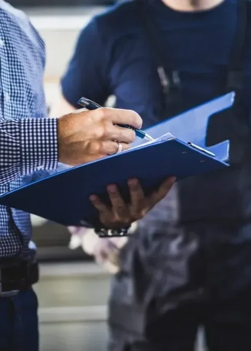 People in a discussion, one person writing in a blue notebook or folder.