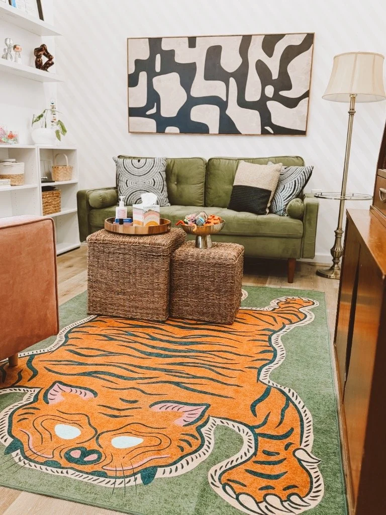 The Art of Being office, with a green sofa, abstract art, and a tiger rug