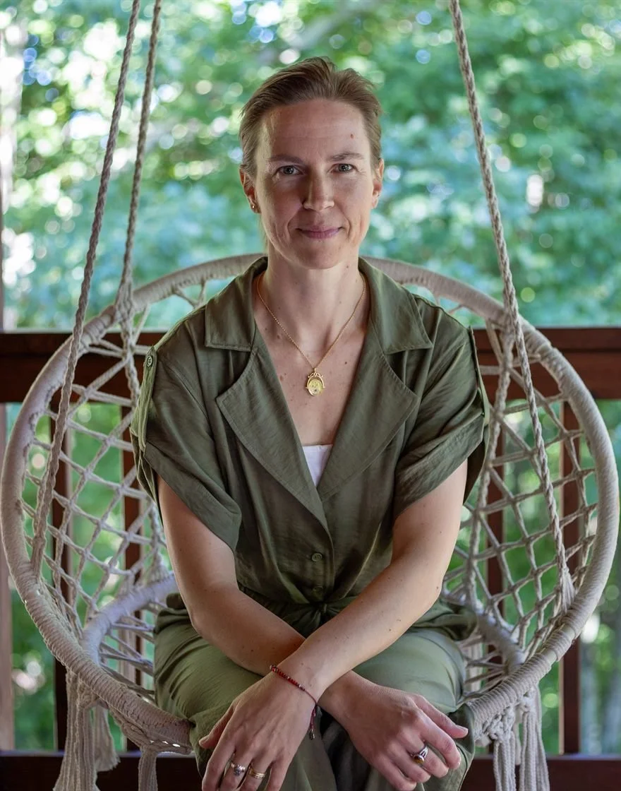 Jenna Manning, LMFT, seated on a hanging porch swing chair surrounded by greenery