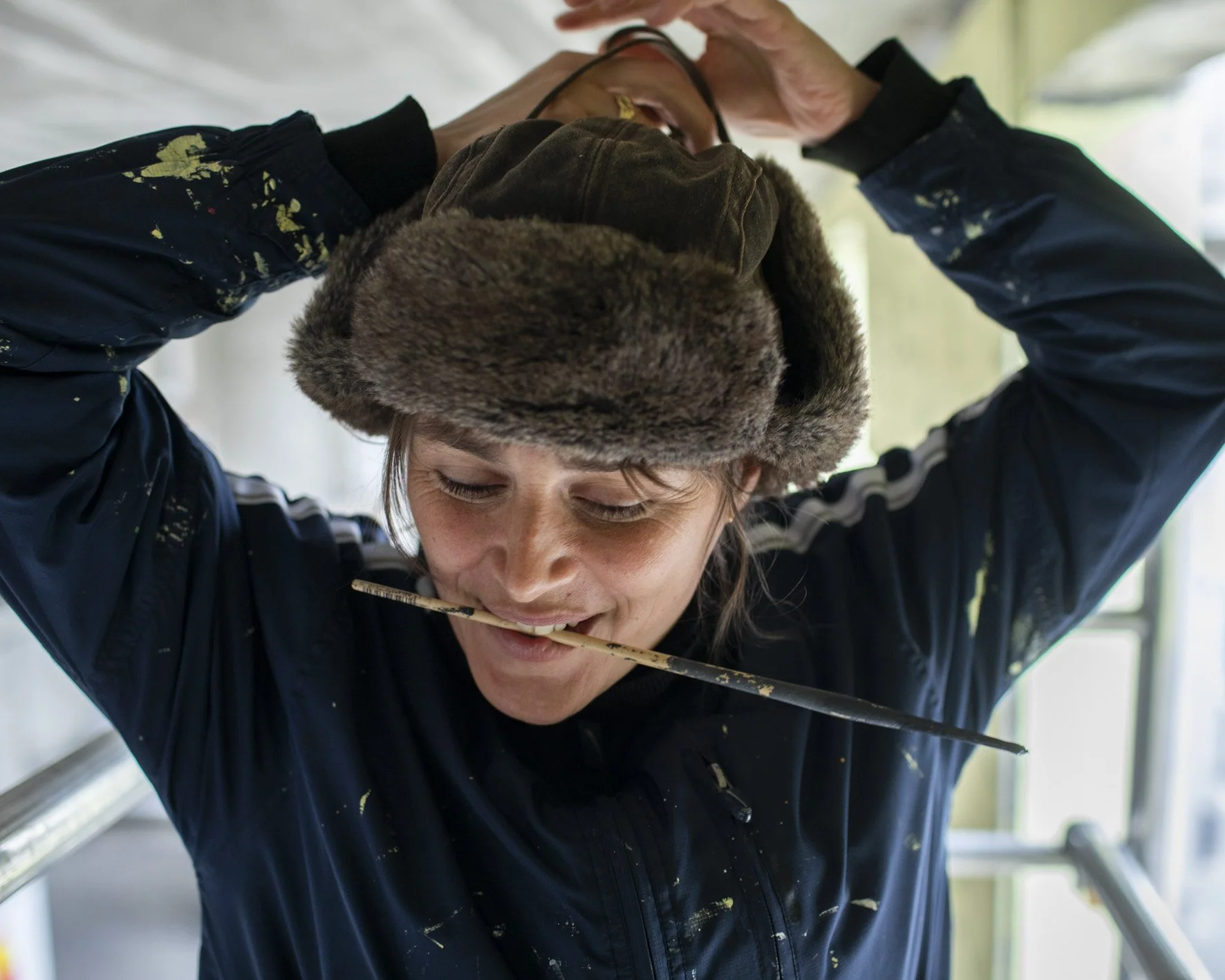 Peintre portant un bonnet en fourrure et tenant un pinceau entre ses dents