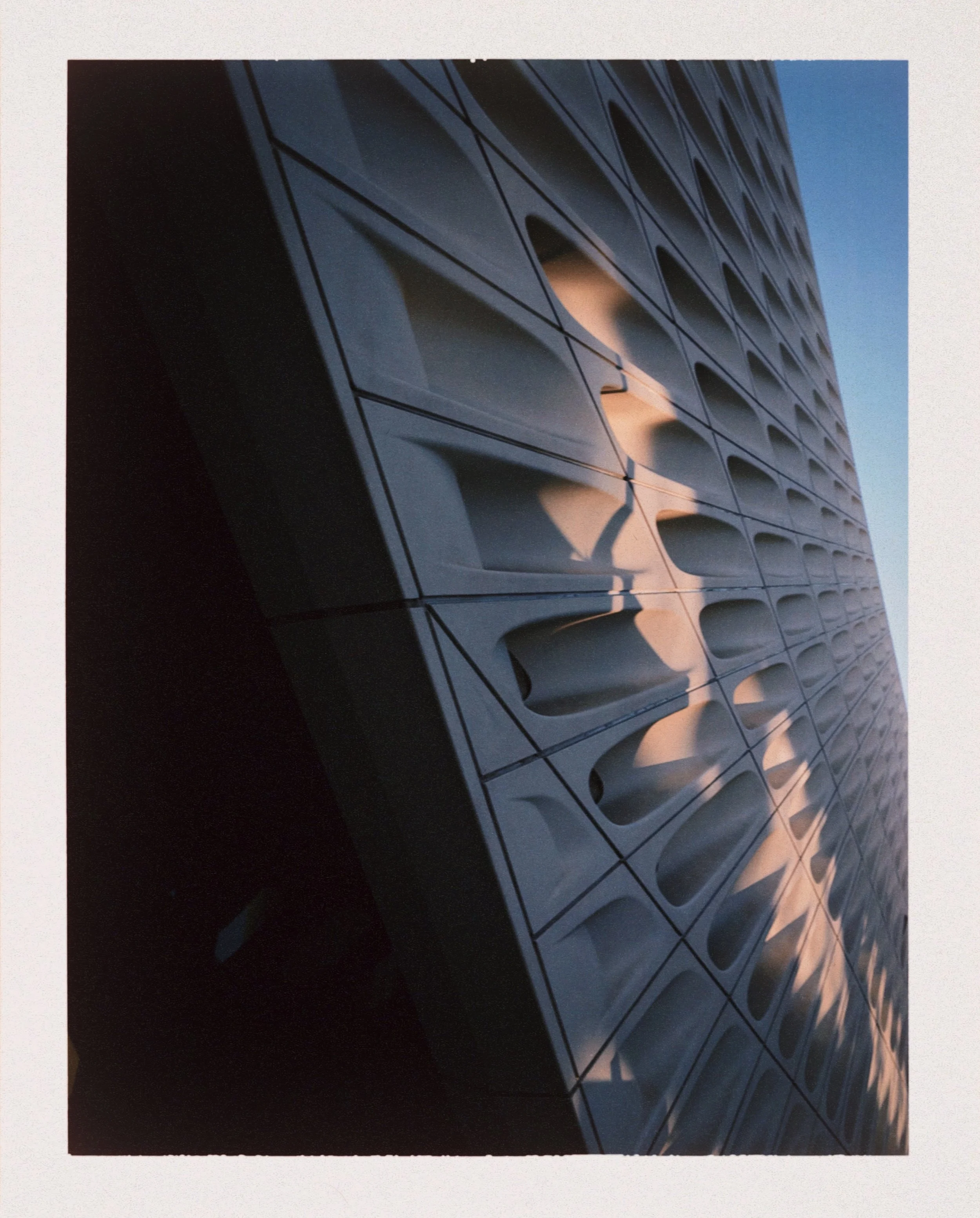 Close-up of a modern glass building reflecting the sky and sunlight.