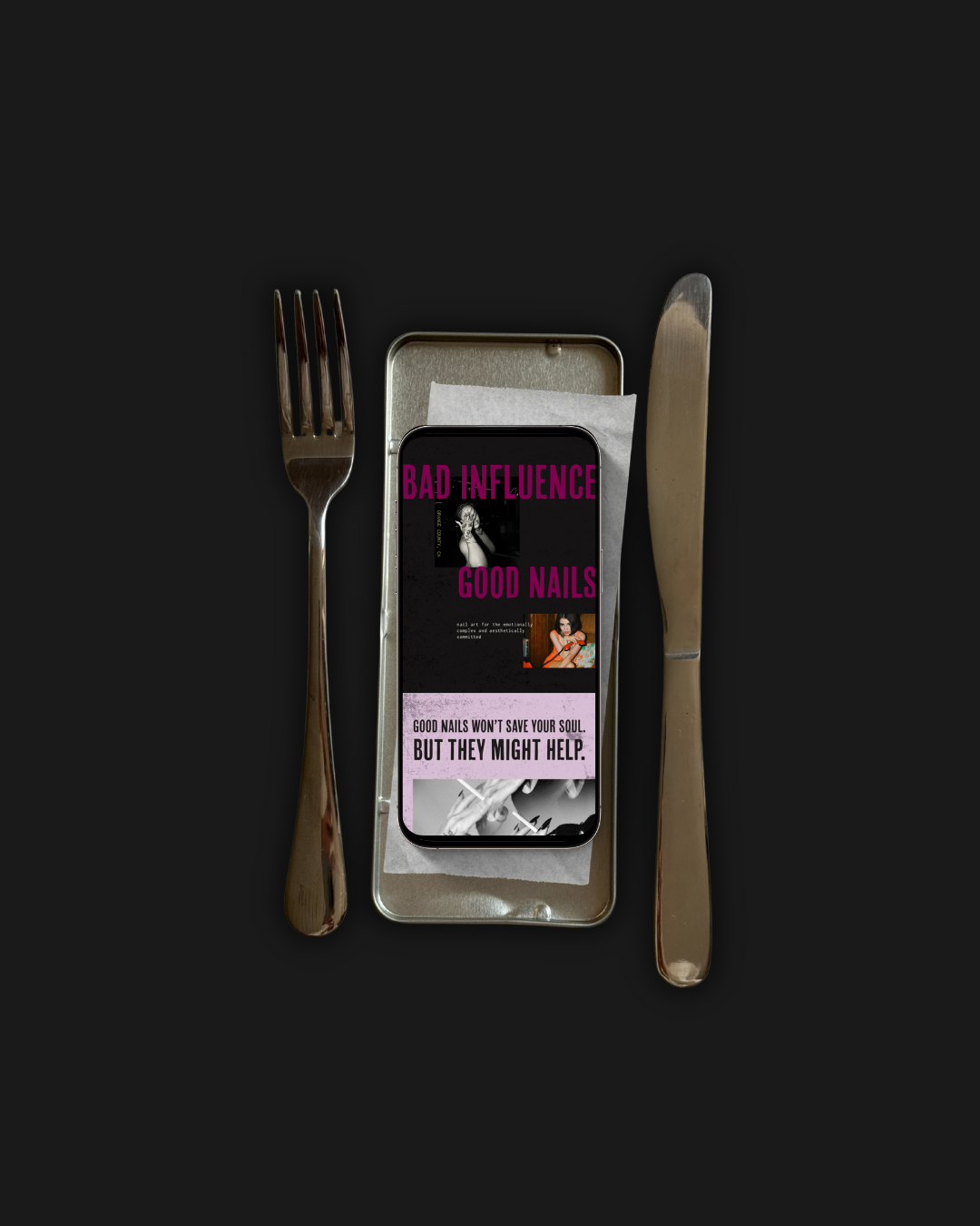 A smartphone displaying a magazine cover with the text 'Bad Influence, Good Nails' surrounded by a fork on the left, a knife on the right, and a silver food container with a paper napkin underneath. The background is black.