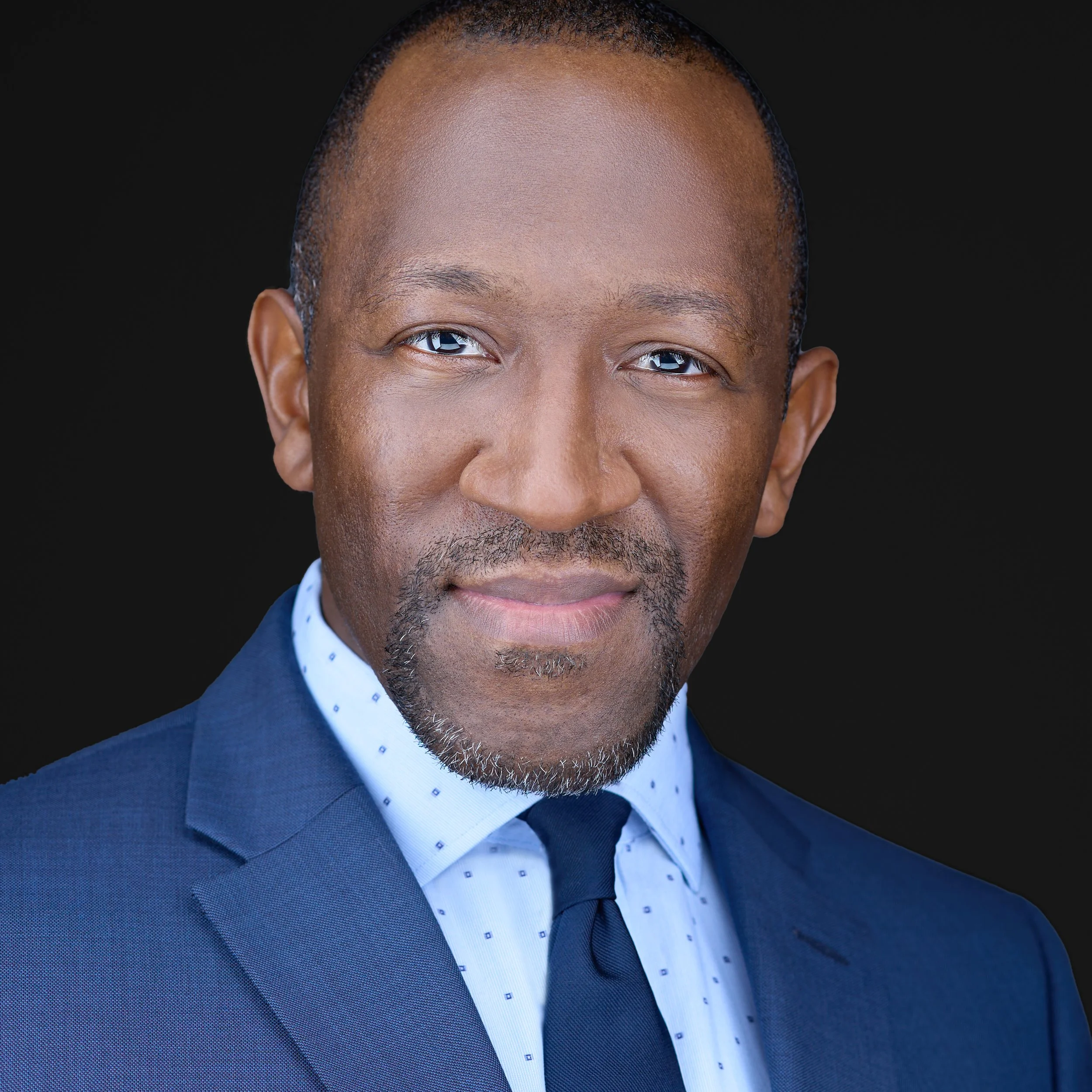 DAVIDSAGGIO Photography Tampa black male executive leadership portrait. Blue patterned shirt, blue jacket, black background.