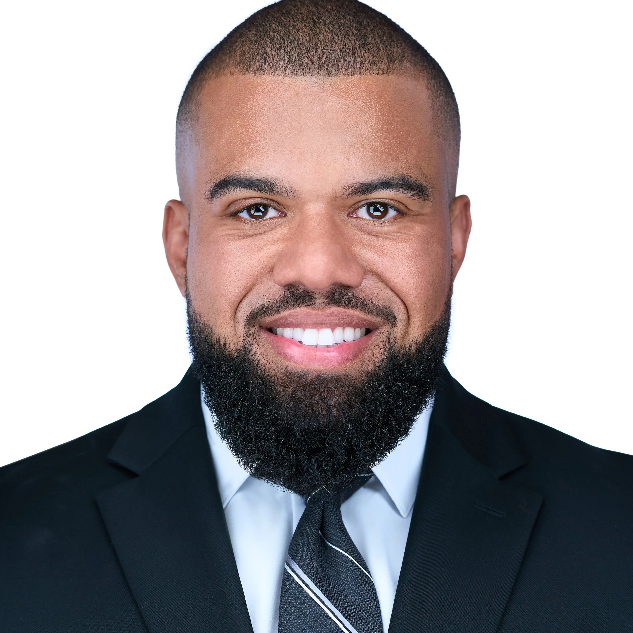 DAVIDSAGGIO Photography Tampa black male executive headshot. Wearing light blue shirt, gray striped tie, and dark gray jacket against white background.