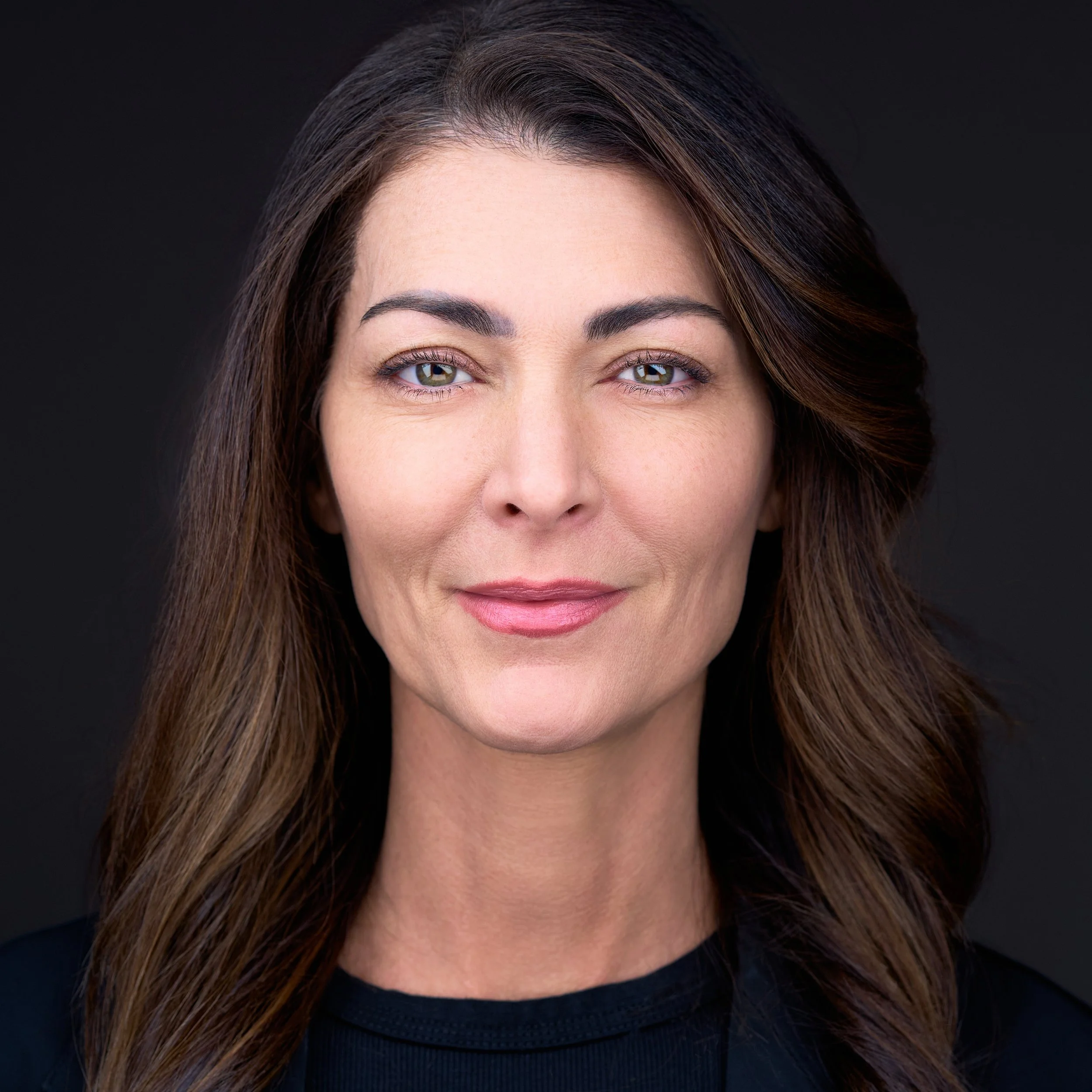 DAVIDSAGGIO Photography Tampa female entrepreneur portrait. Brunette with exotic look. Wearing black top against black background.