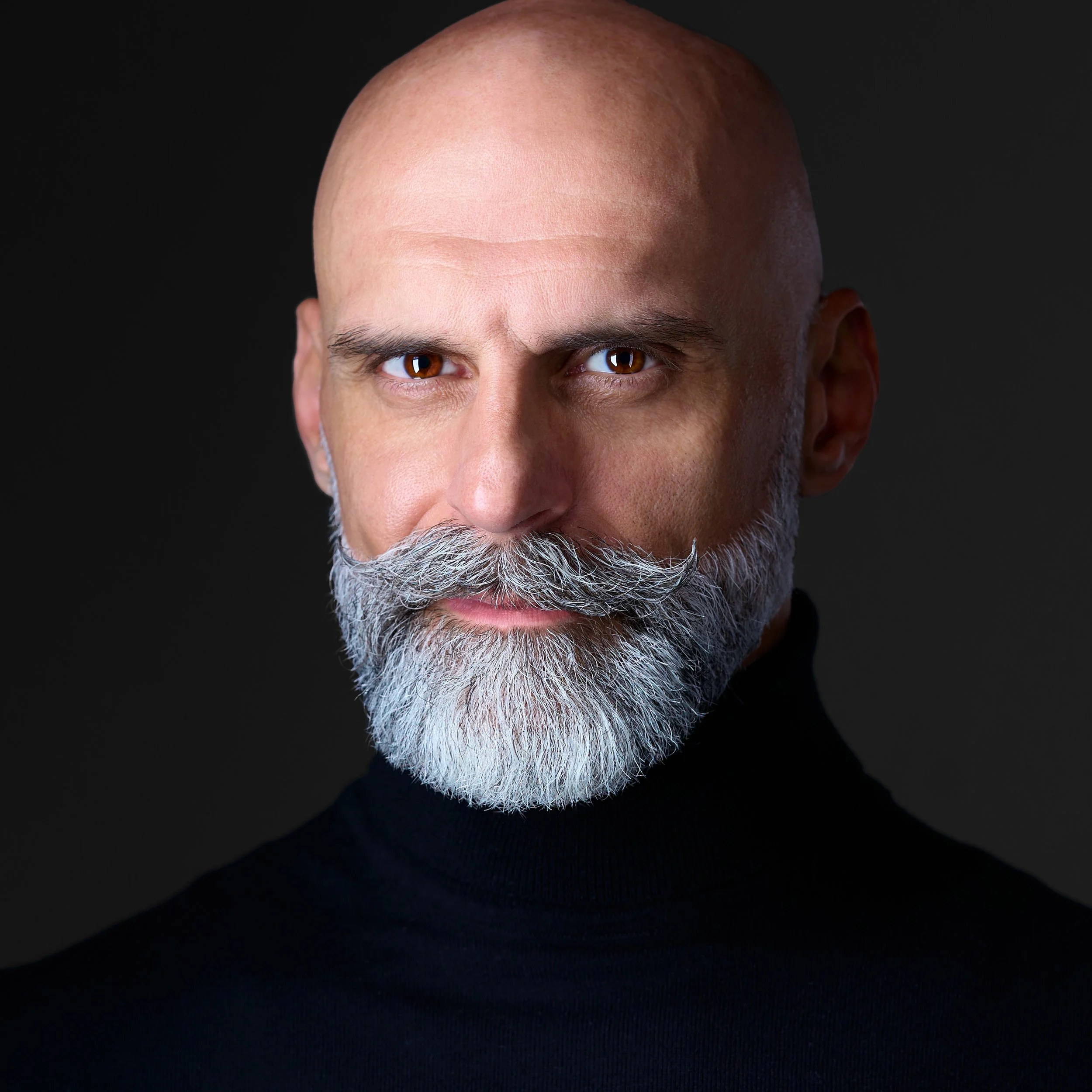 DAVIDSAGGIO Photography Tampa entrepreneur portrait. Dramatic lighting. Intense eyes with trimmed beard. Wearing black turtleneck against a black background.