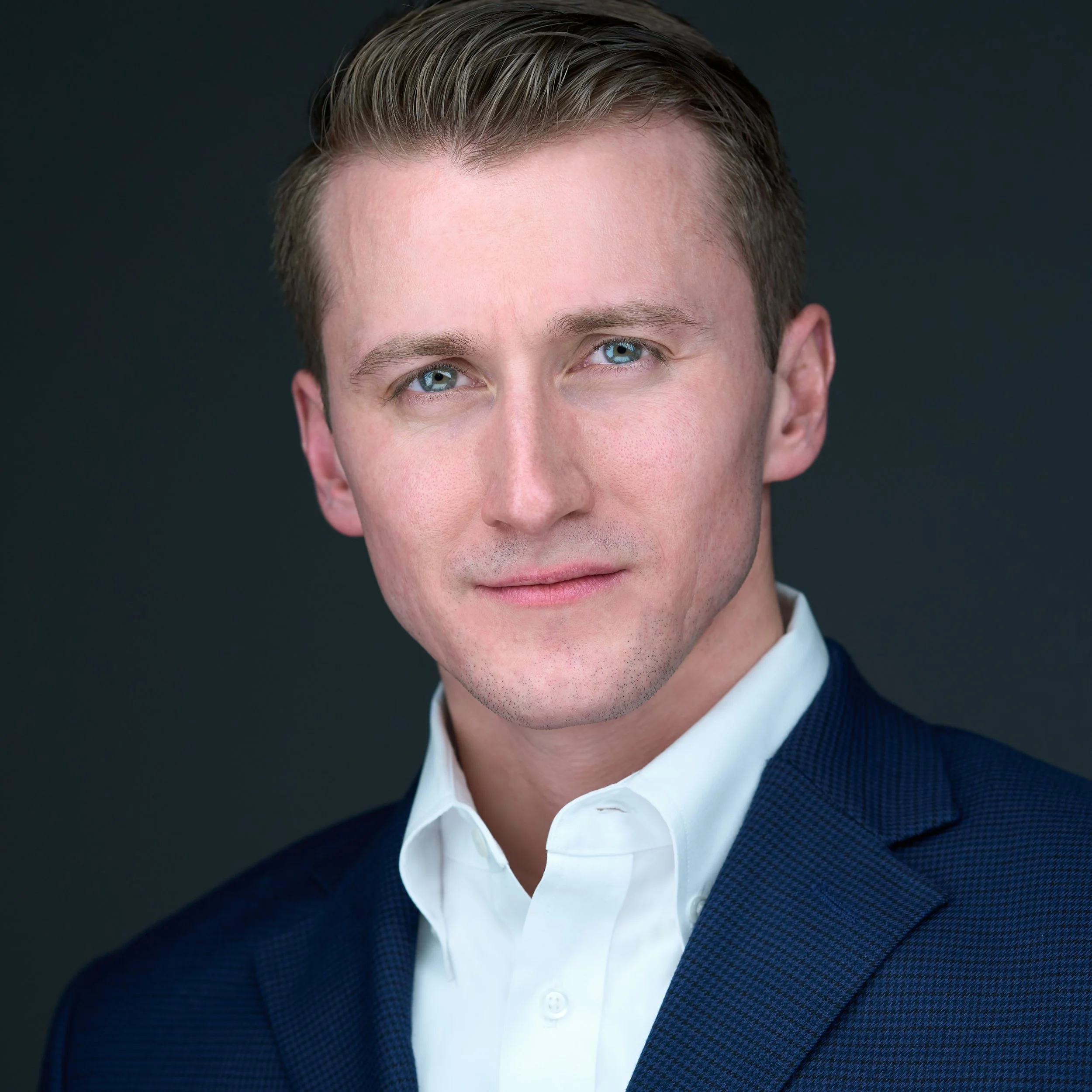 White male executive portrait. Commanding look, wearing a white button down shirt, dark navy jacket on a black background. DAVIDSAGGIO Photography Tampa.