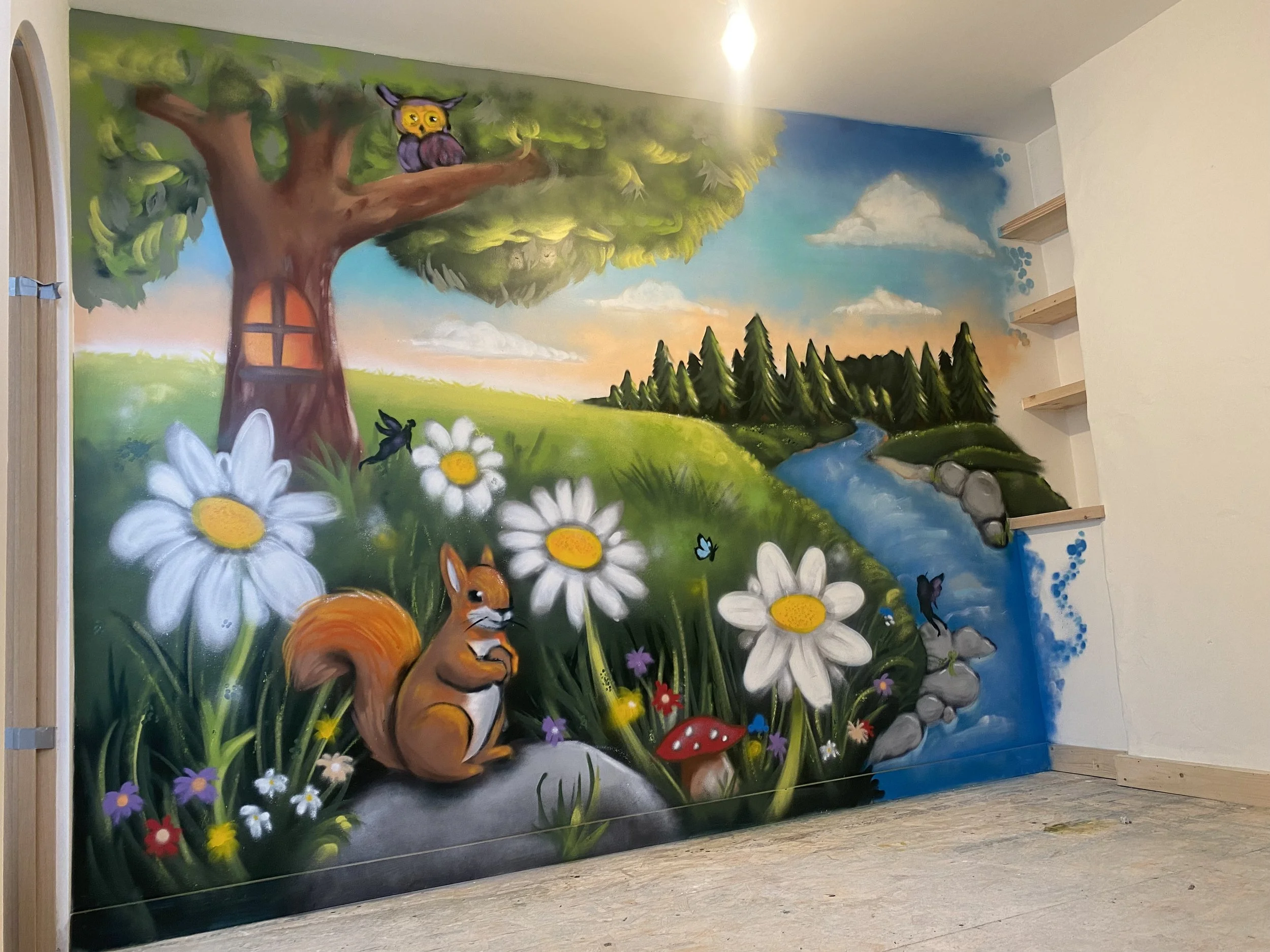 Colorful mural featuring a large tree with a bird in a nest at the top, a stream flowing through a grassy landscape, various flowers including daisies, mushrooms, and small animals such as a squirrel and birds, set against a vibrant sky with clouds.