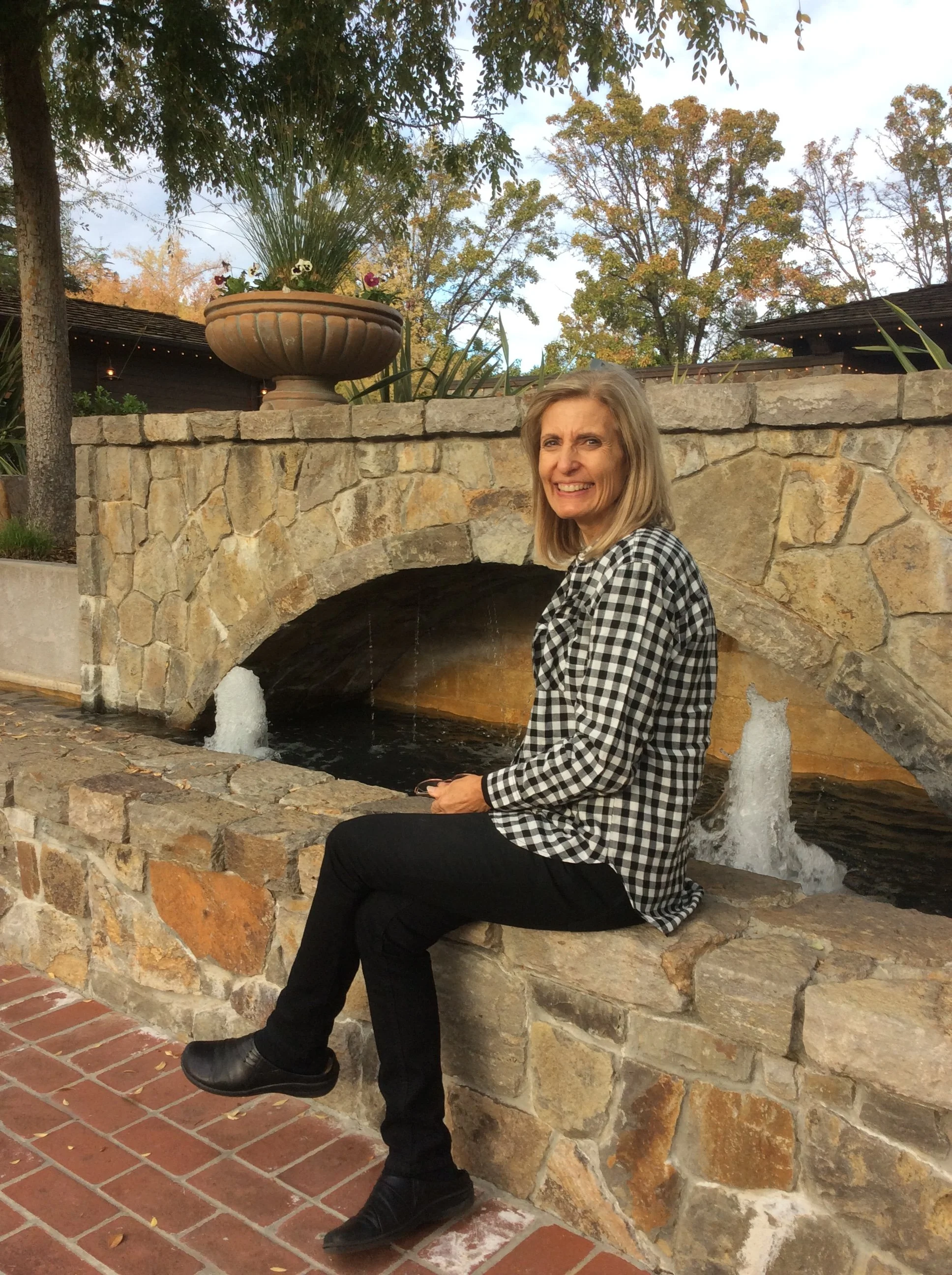 Donna smiling beside a stone fountain