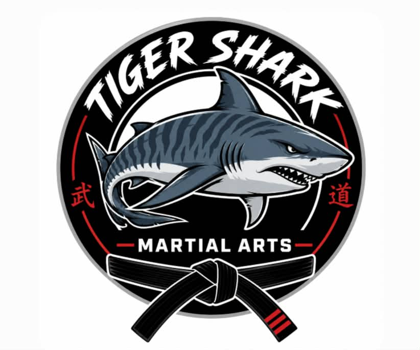 A logo for Tiger Shark Martial Arts featuring a fierce shark with a black belt, black and red text, and Japanese characters.