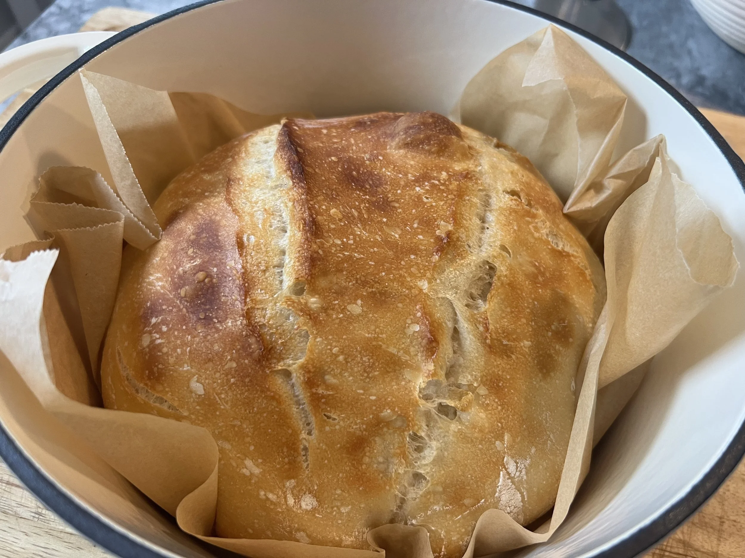A round loaf of bread in a paper-lined basket.