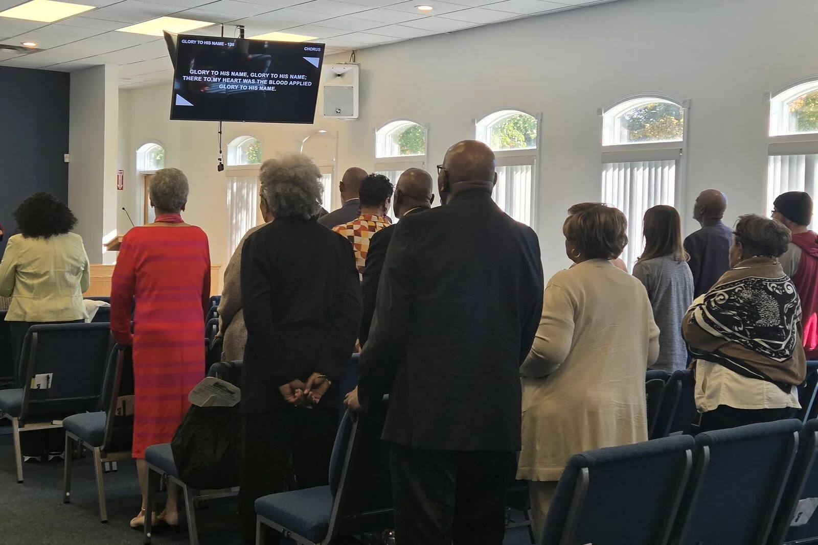 Members of People’s Community Church standing and singing during worship in the sanctuary.