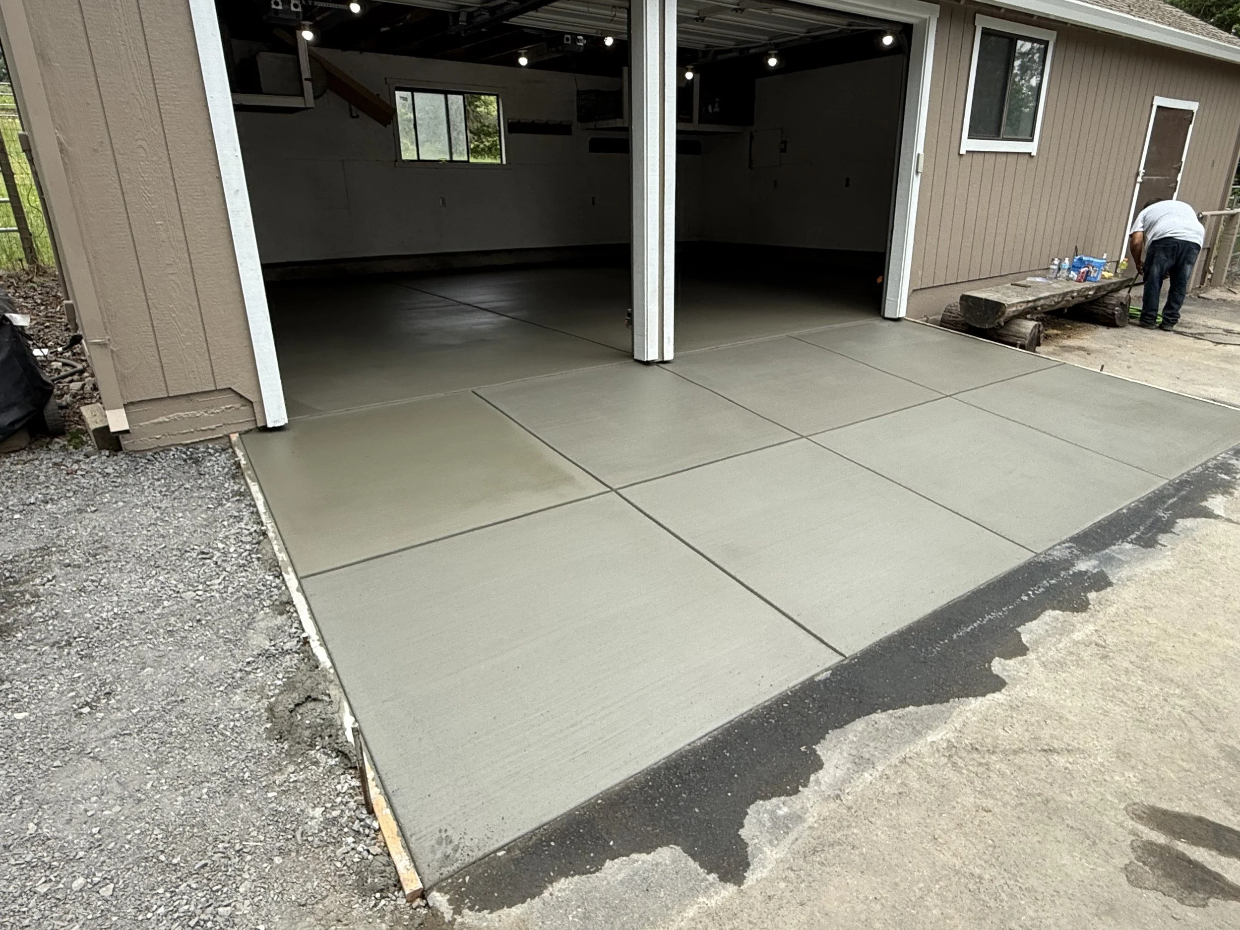 A newly poured concrete apron outside a garage.