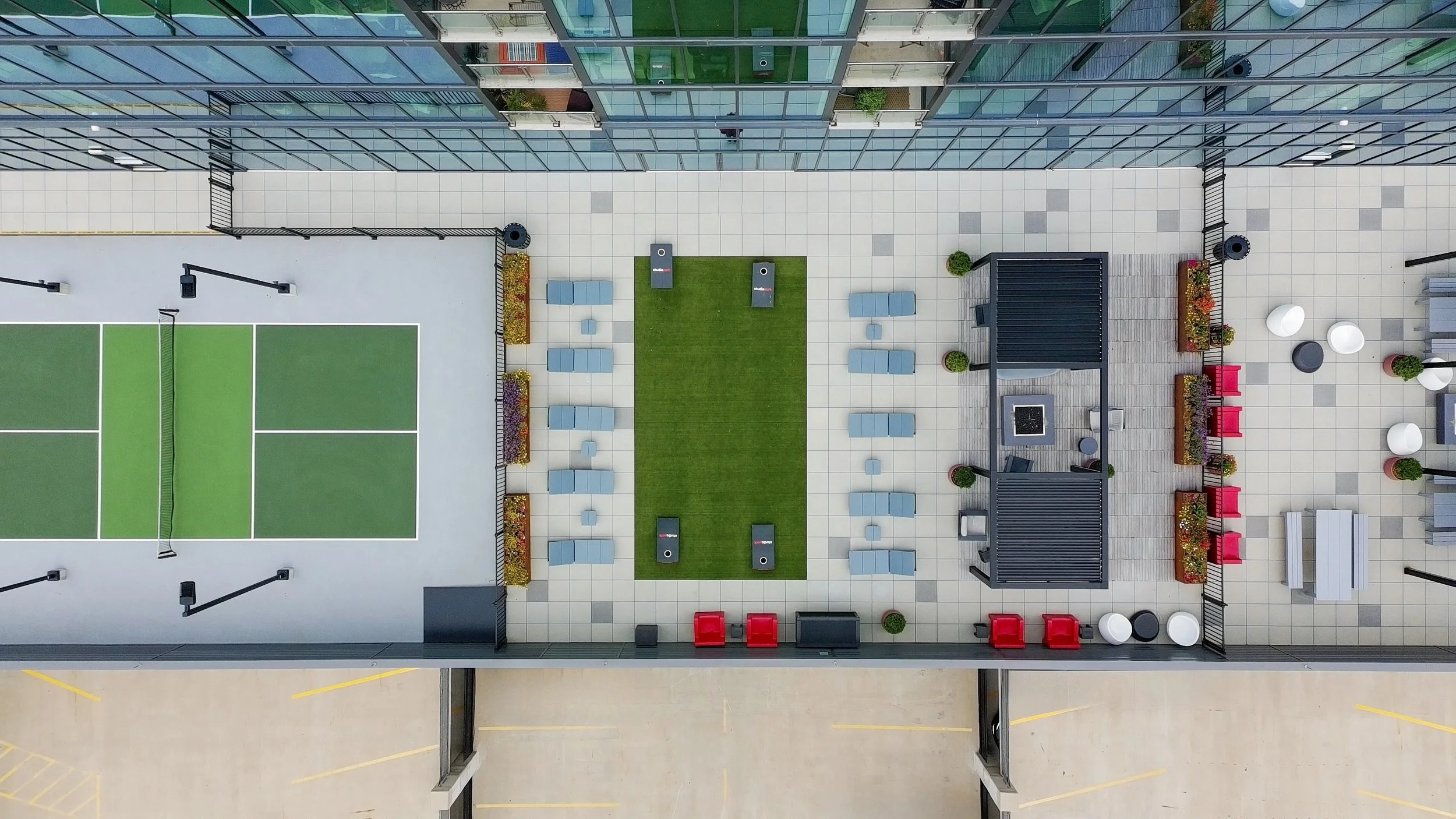Top-down view of a modern rooftop terrace with sports courts, seating areas, and decorative plants.
