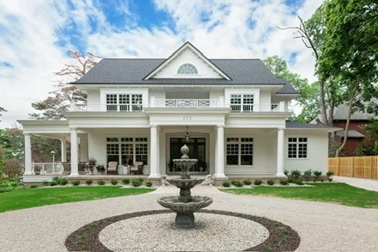 Large white two-story house with a fountain in front and a circular gravel driveway