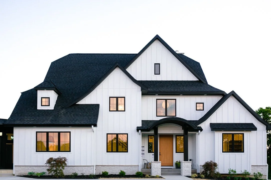 Modern white house with black roof and multiple windows.