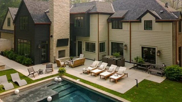 Backyard view of a modern house with a swimming pool, outdoor seating, and lounge chairs.