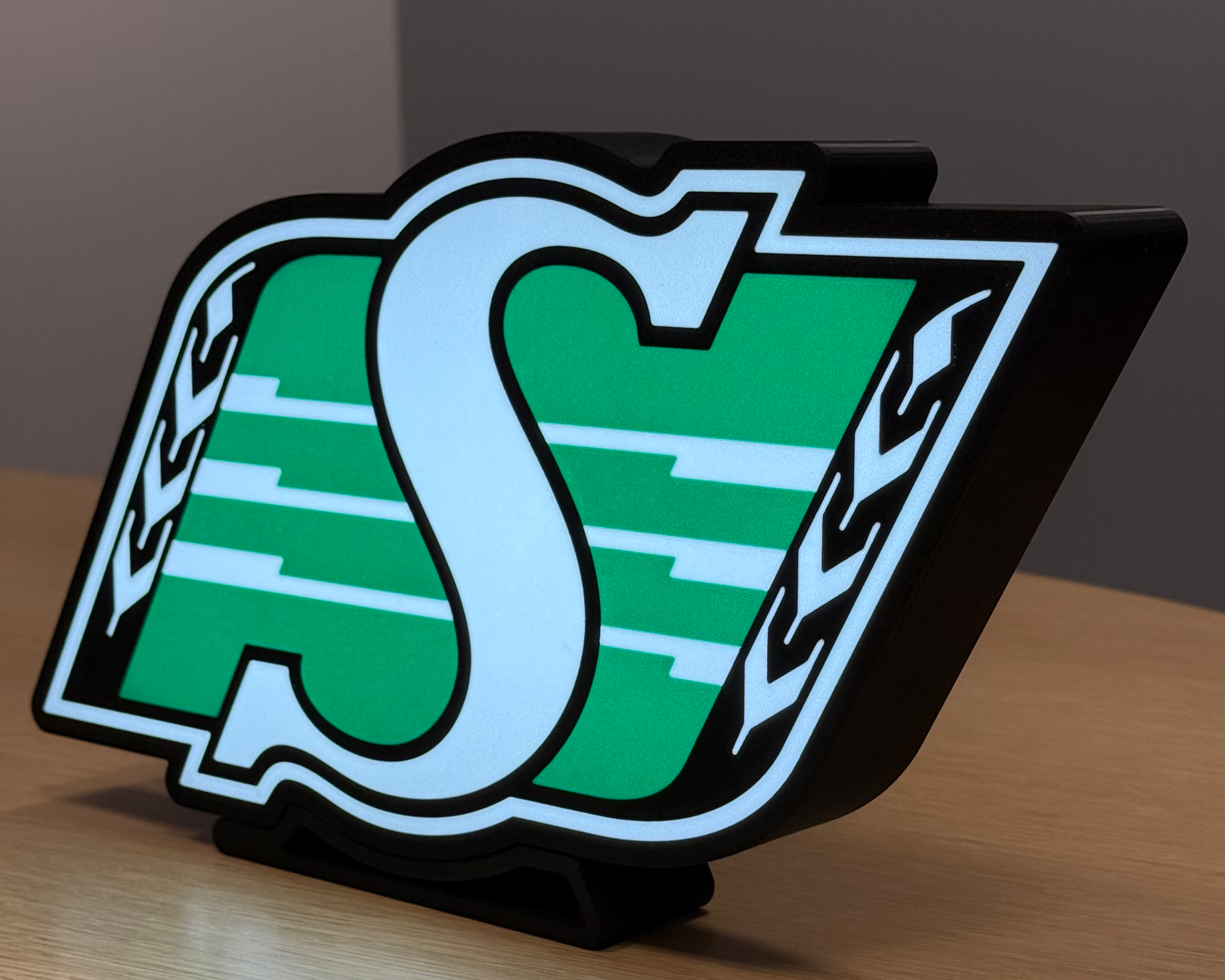 Illuminated angled view of the Saskatchewan Roughriders logo lightbox with warm ambient lighting