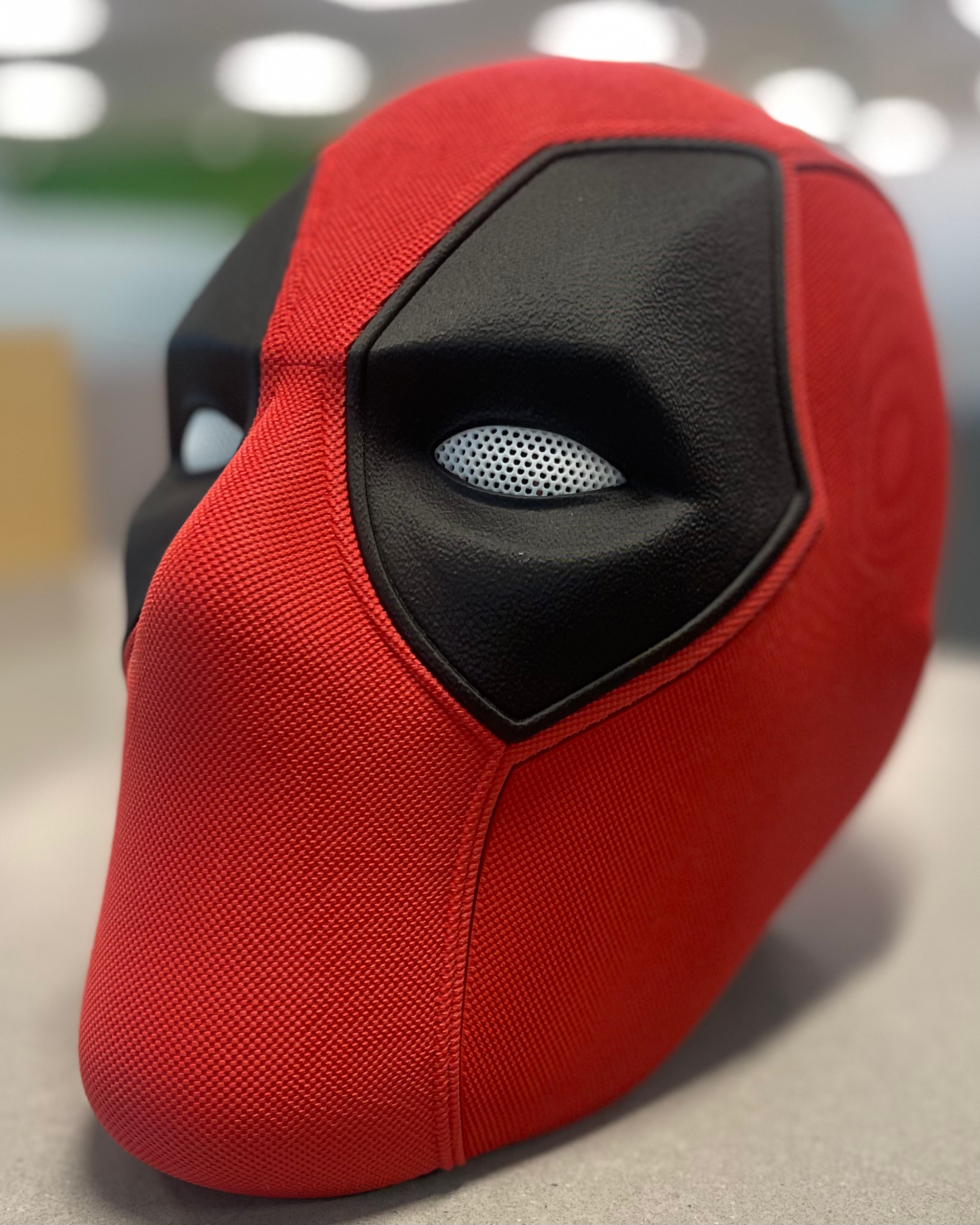 Close three-quarter view of the Deadpool mask highlighting the sculpted eye area and contrasting red and black textures
