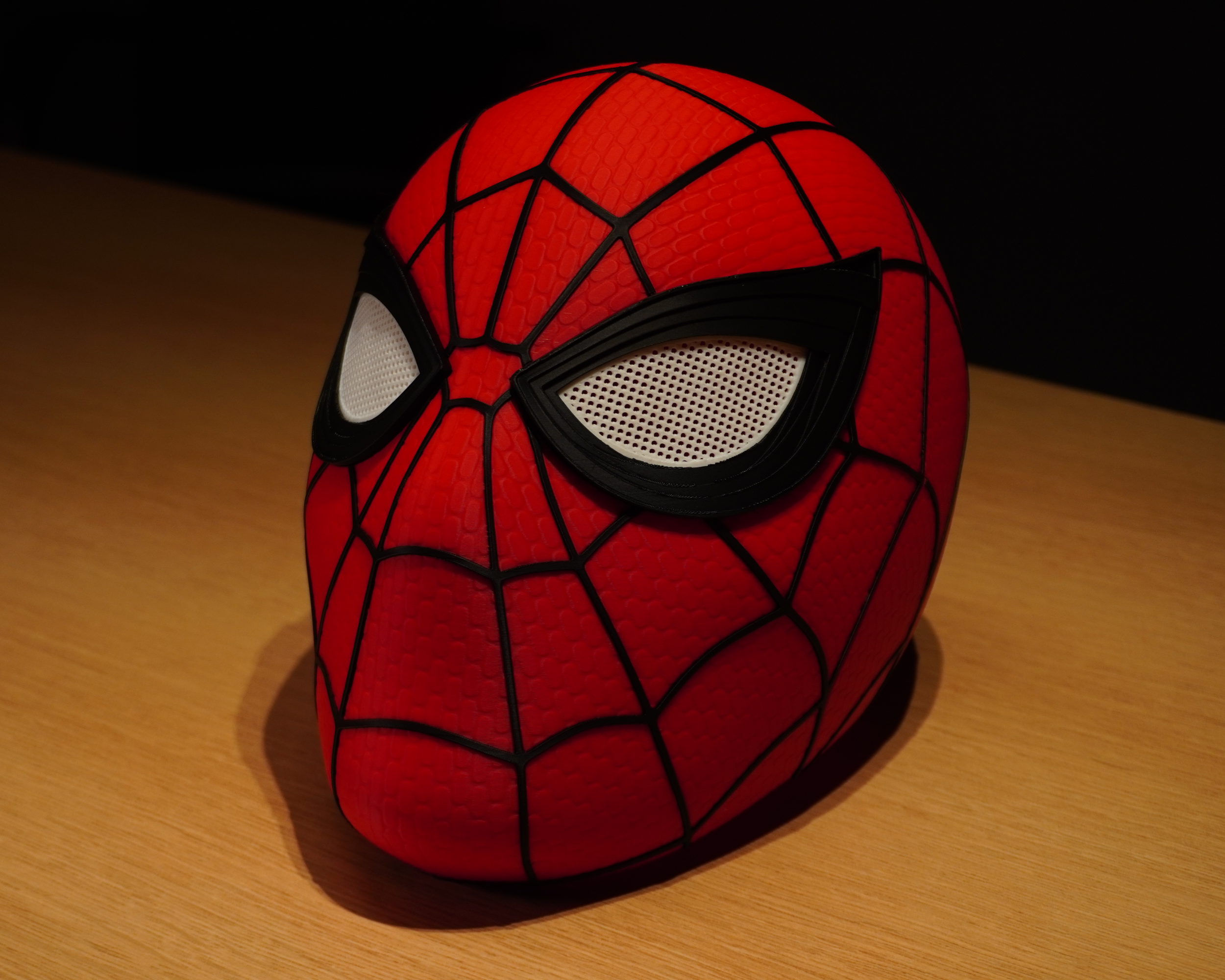 Three-quarter front view of the 3D-printed Spider-Man mask showing the raised web pattern and removable eye pieces