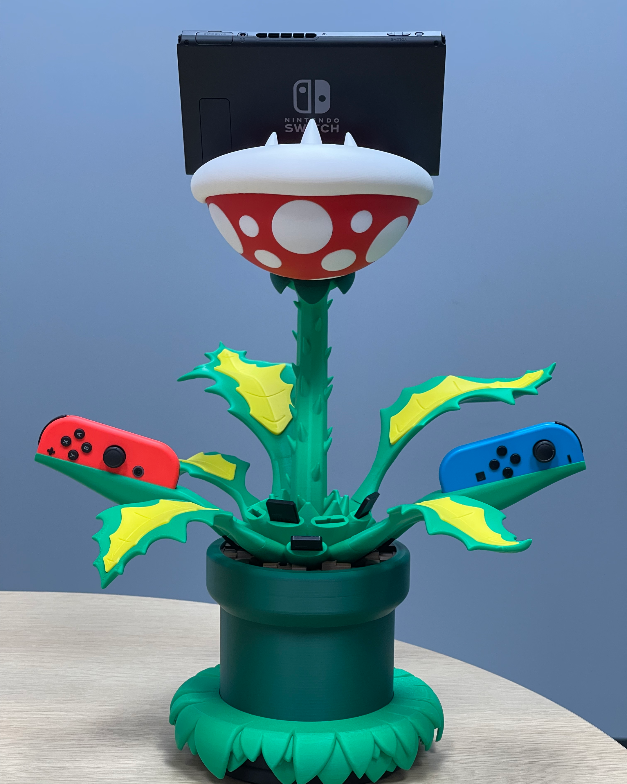 Front view of the 3D-printed Piranha Plant dock holding a Nintendo Switch and two Joy-Con controllers in their charging positions