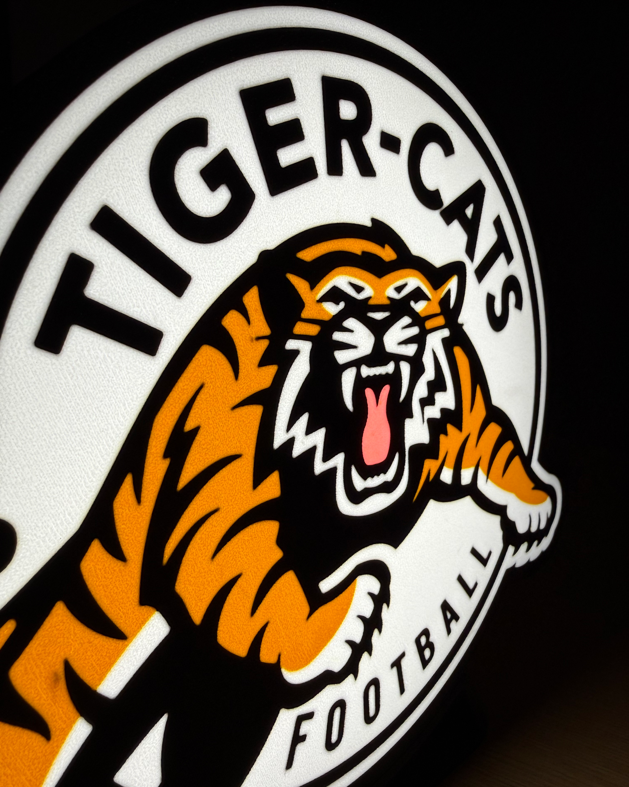 Close angled view of the illuminated Hamilton Tiger-Cats lightbox showing the layered logo details and printed surface texture