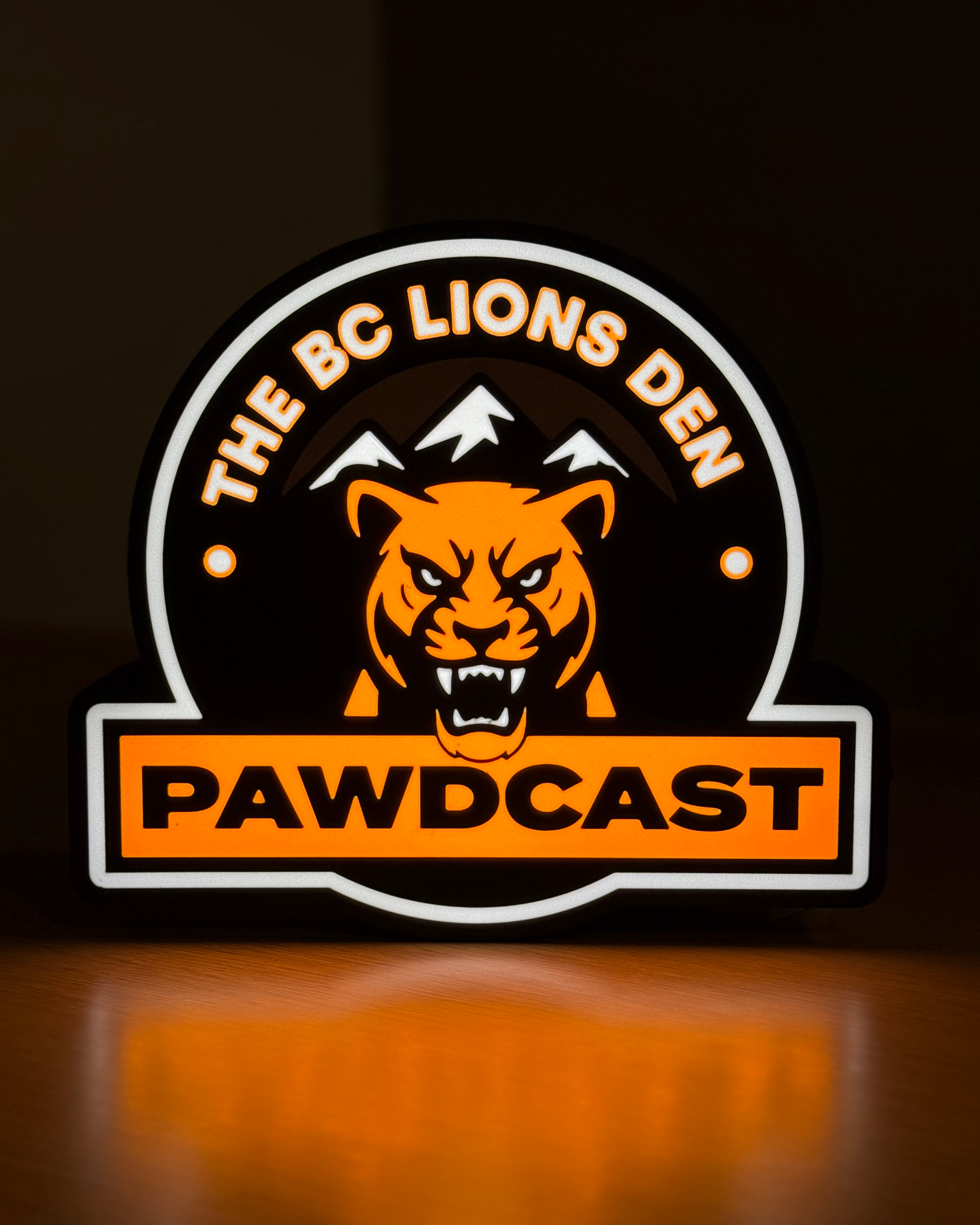 Illuminated front view of the BC Lions Den Pawdcast lightbox against a dark background