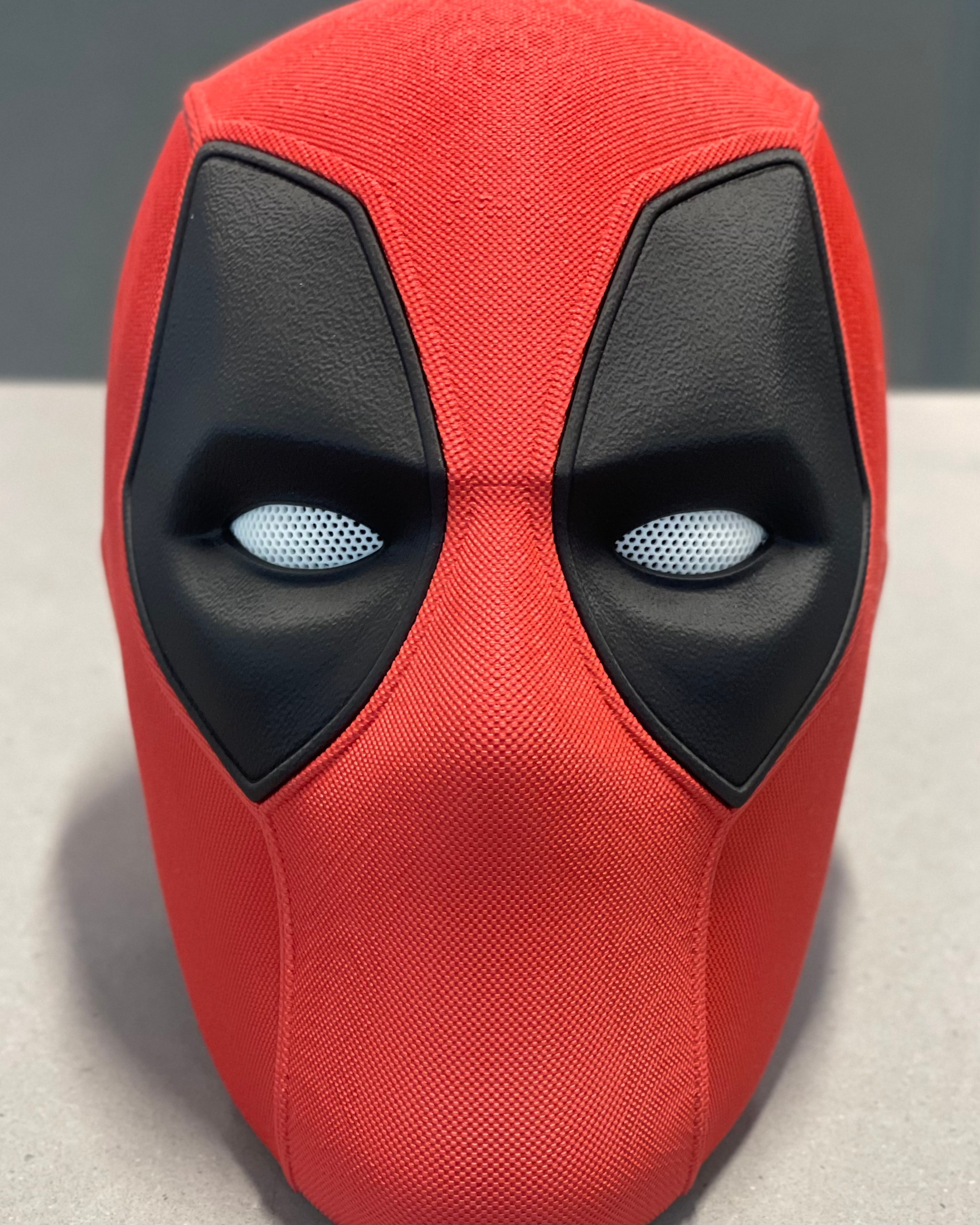 Straight-on front view of the completed 3D-printed Deadpool mask showing the red textured shell, black eye panels, and white mesh inserts