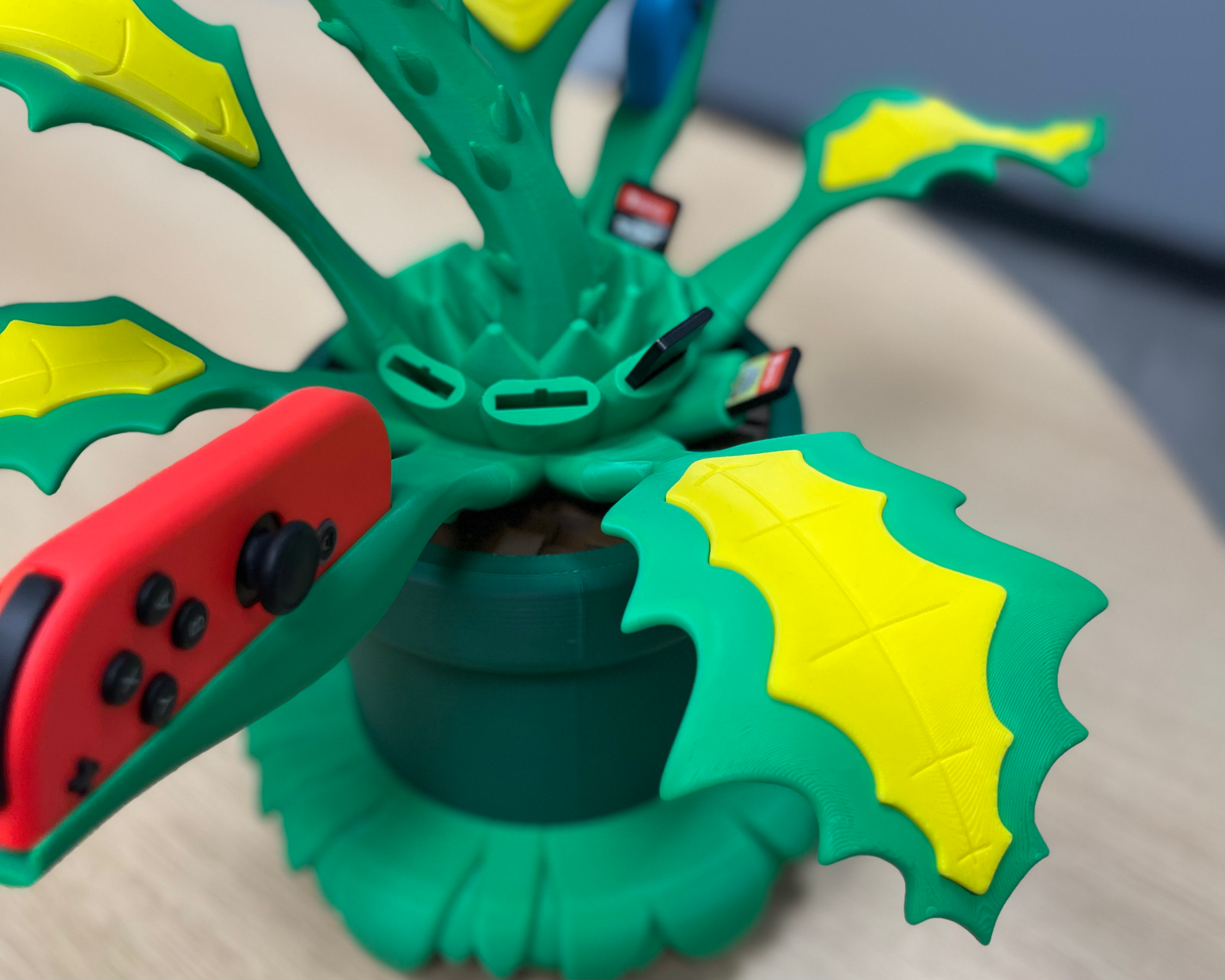 Close-up of the Piranha Plant base showing the Joy-Con charging positions, decorative leaves, and built-in game cartridge storage