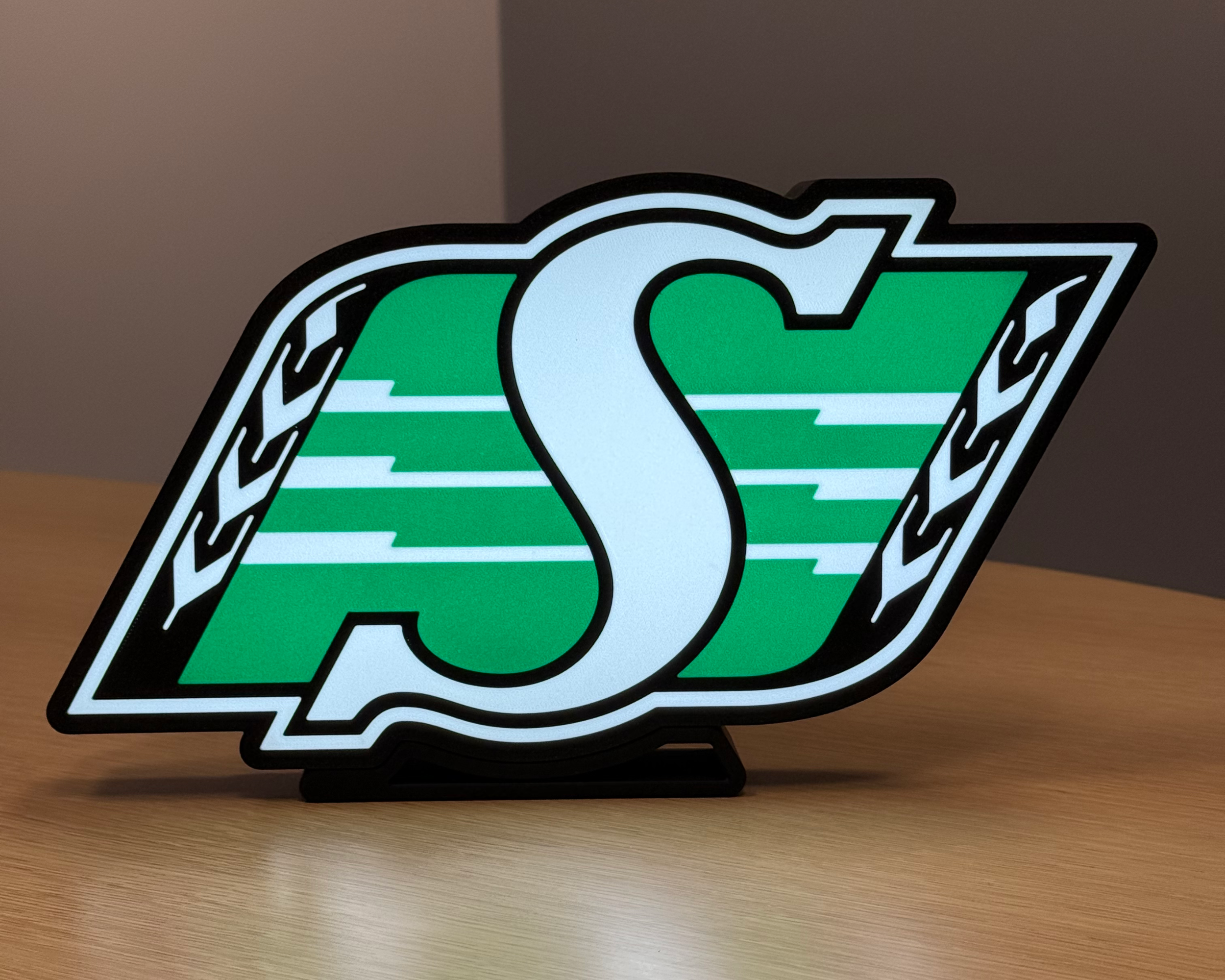 Illuminated front view of the Saskatchewan Roughriders logo lightbox with warm ambient lighting