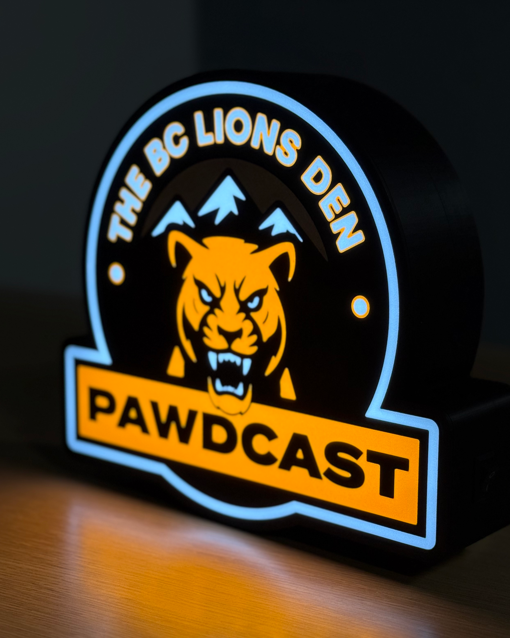 Illuminated angled view of the BC Lions Den Pawdcast lightbox showing the housing depth and glowing edge details