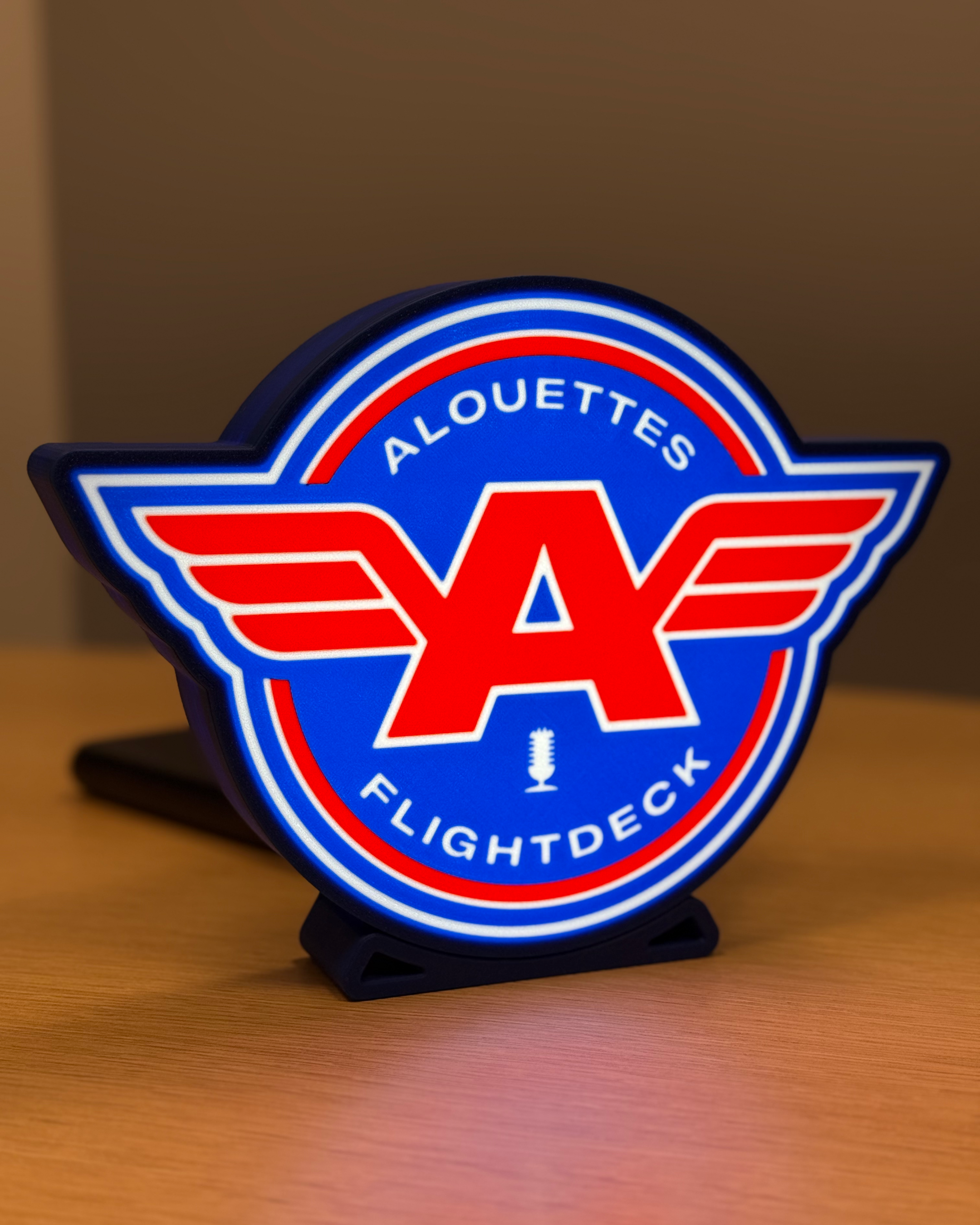 Illuminated front view of the Alouettes Flightdeck Podcast lightbox with warm ambient lighting